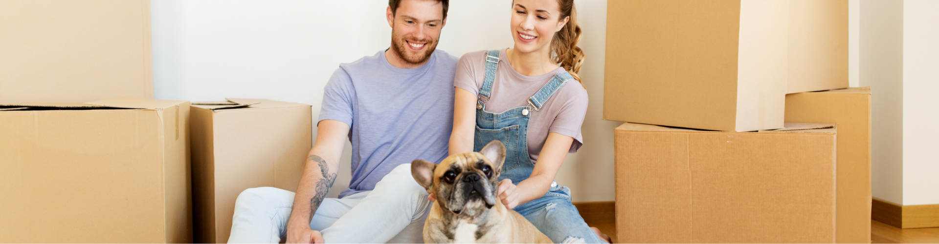 A man and a woman with a dog in a room with boxes.
