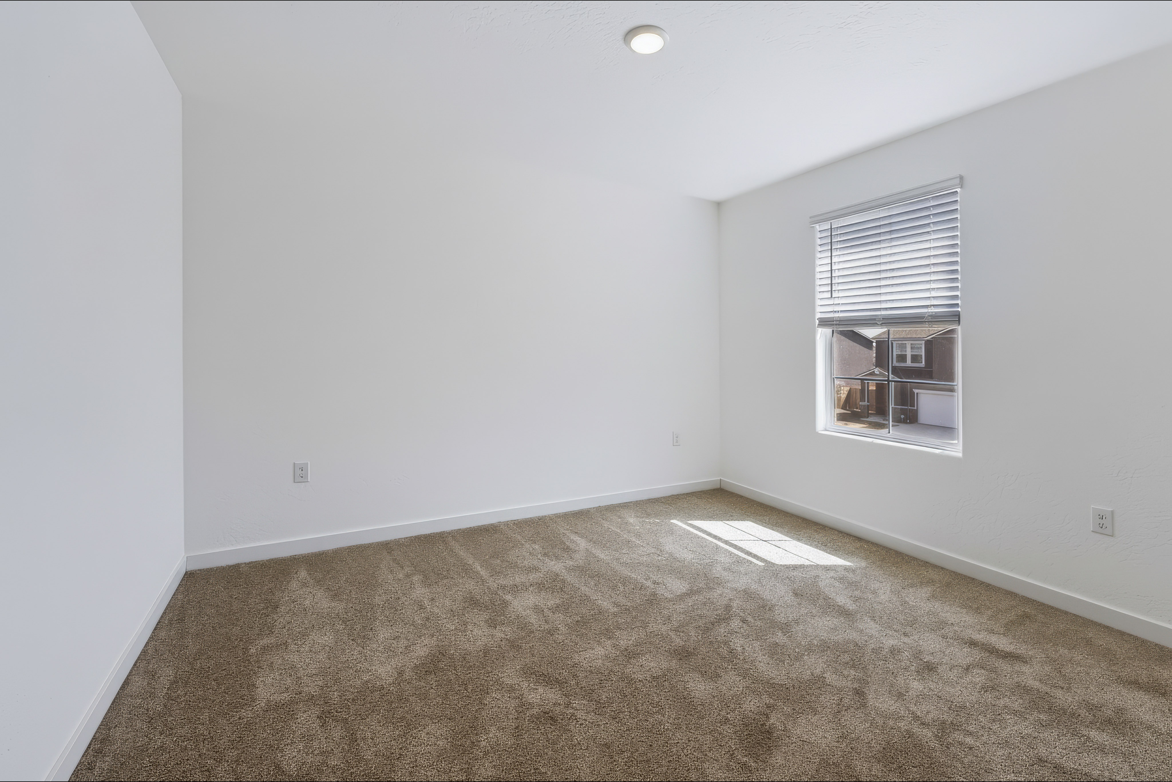 A room with a carpet and a window.
