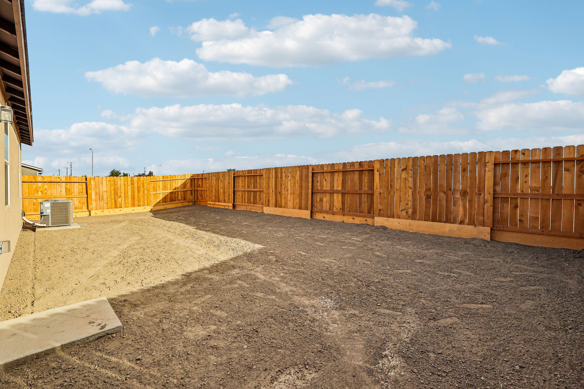 A fenced off area with a dirt road and a building in the background.
