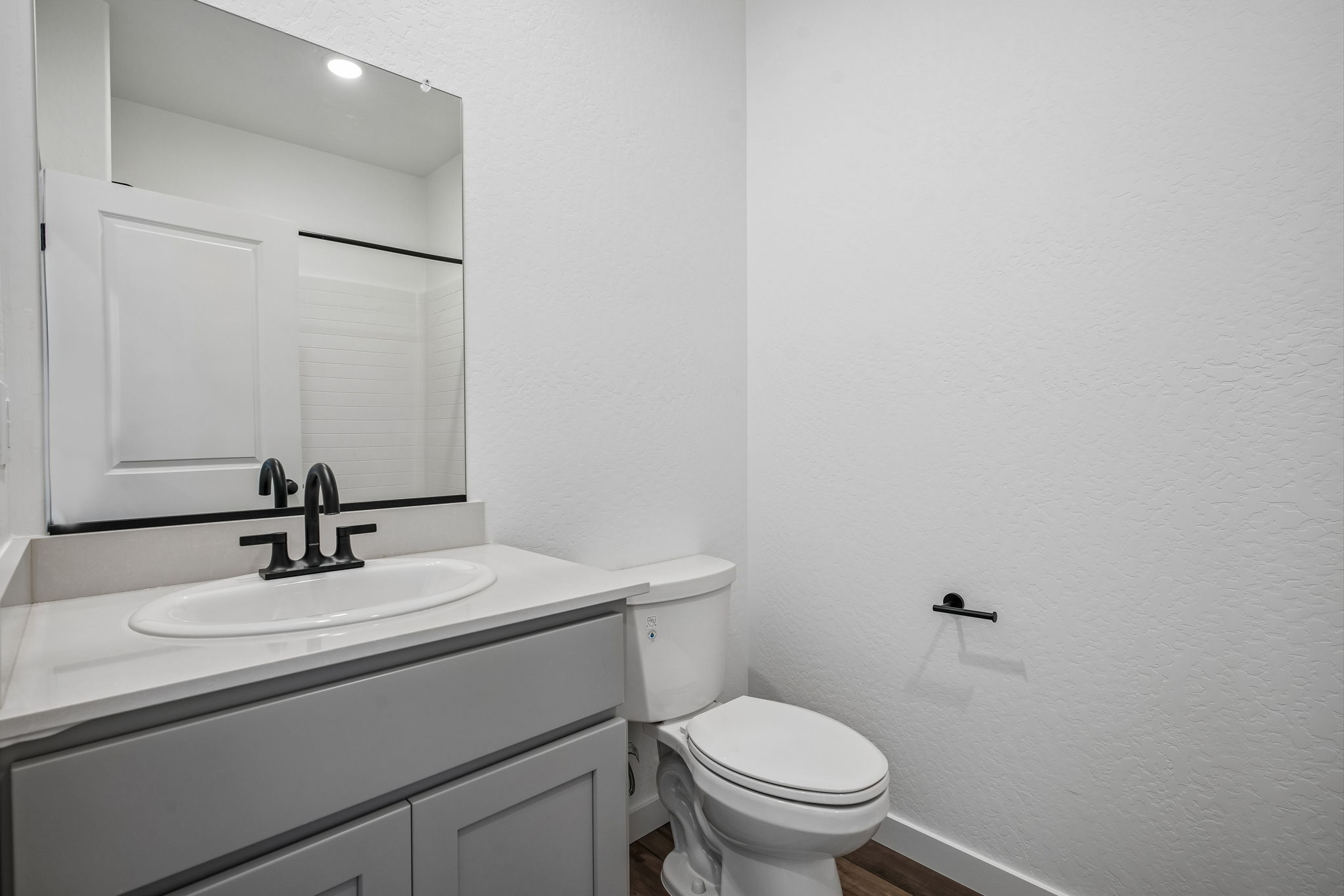 A bathroom with a sink toilet and mirror.