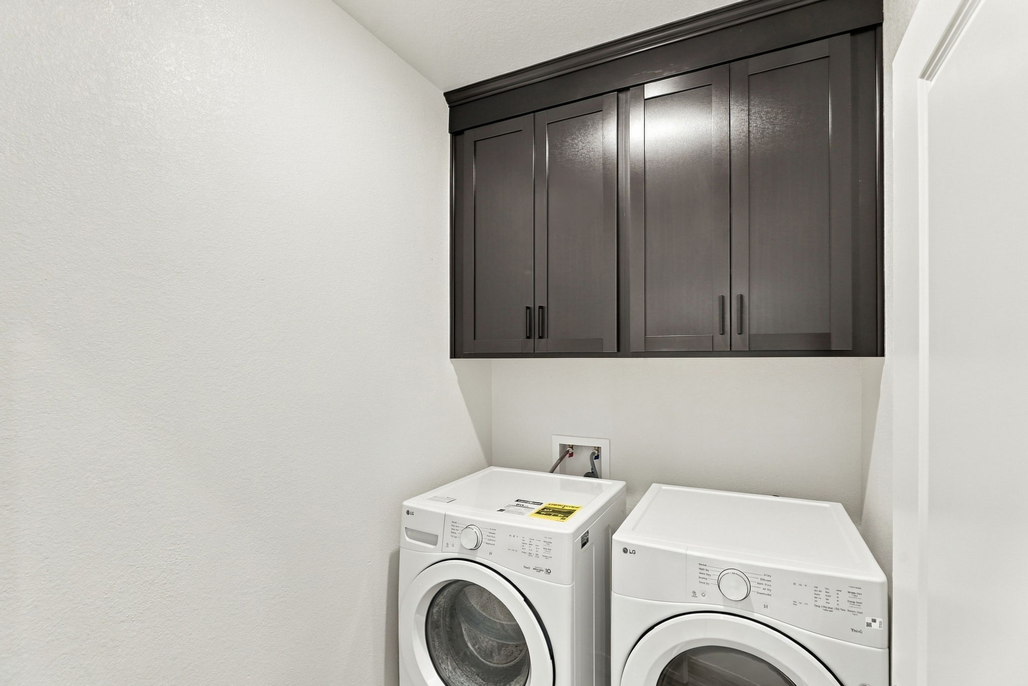 A white laundry room with a black cabinet and a dryer.