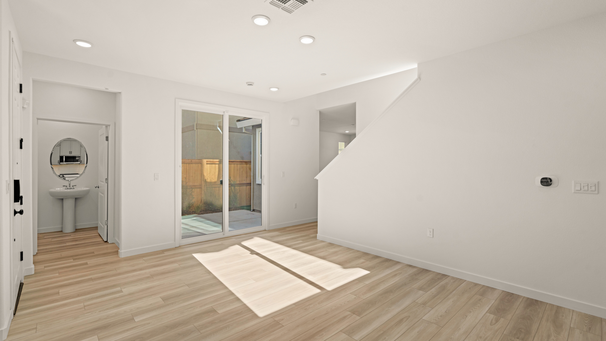 A room with a wood floor and a white wall with a mirror.