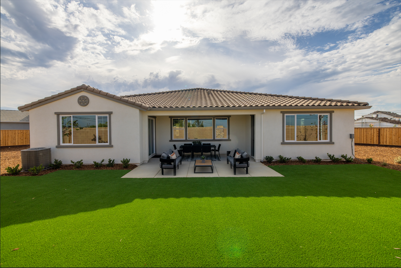 A house with a lawn and a table and chairs in the front.