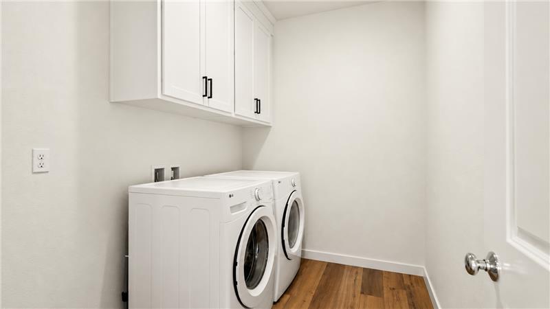A white room with a washing machine and white cabinets.