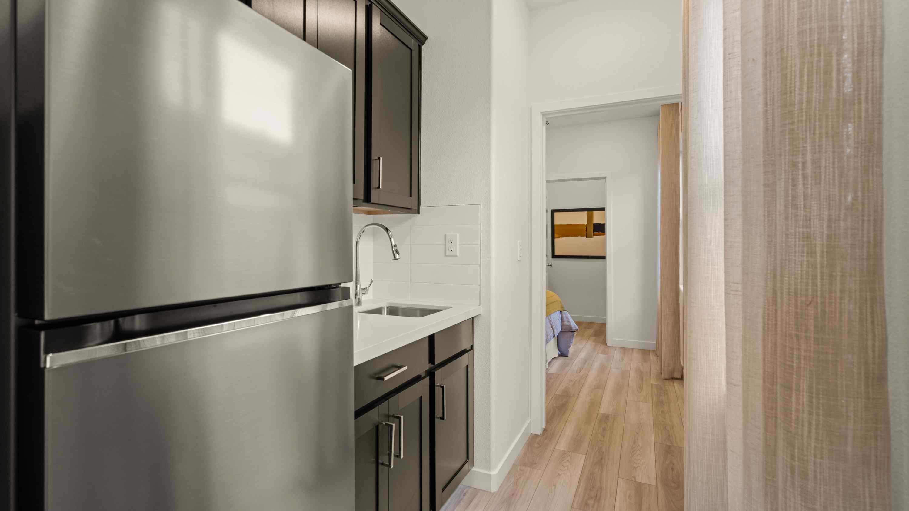 A kitchen with a refrigerator and a sink.