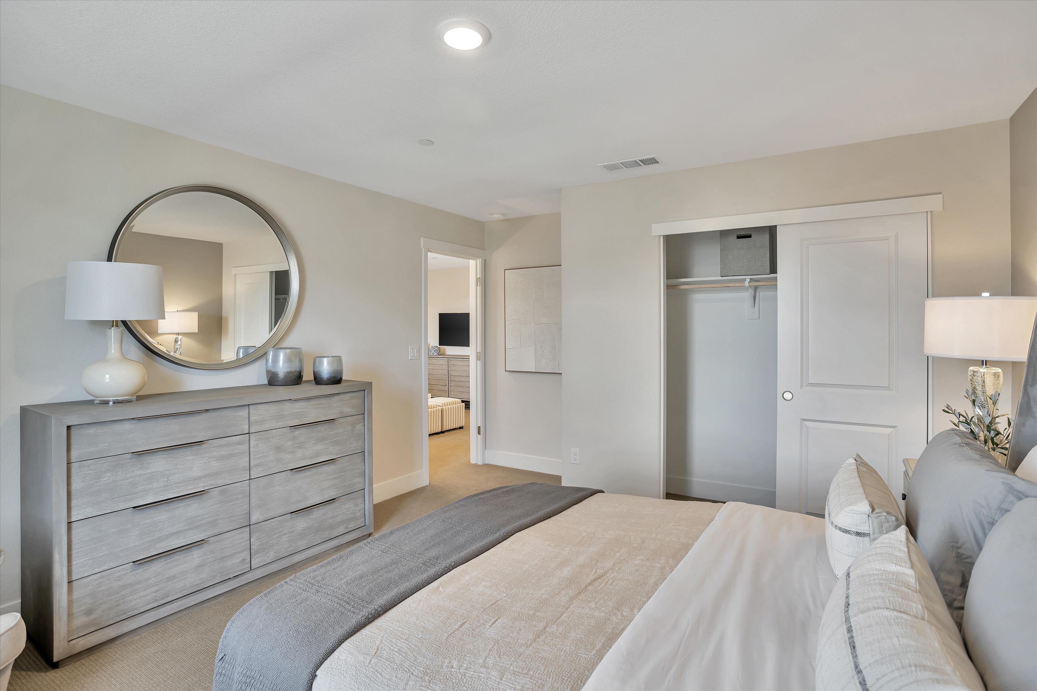 A bedroom with a bed and a mirror.