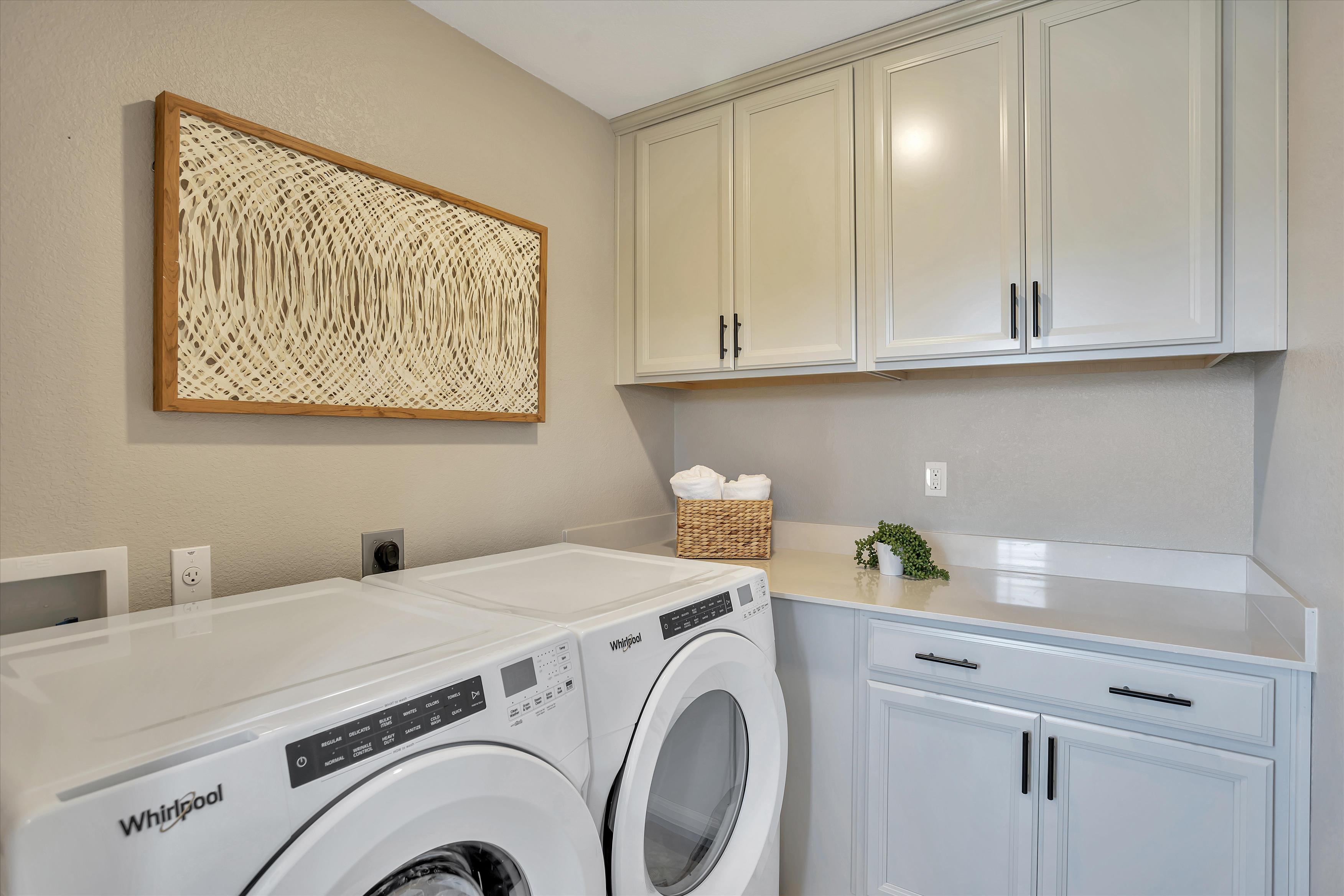 A laundry room with white cabinets.