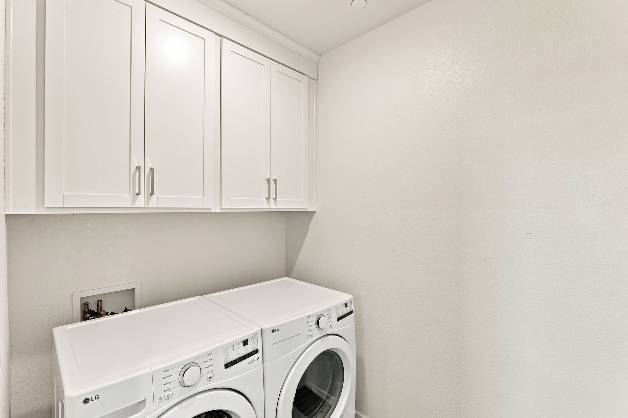 A white laundry room with white cabinets.
