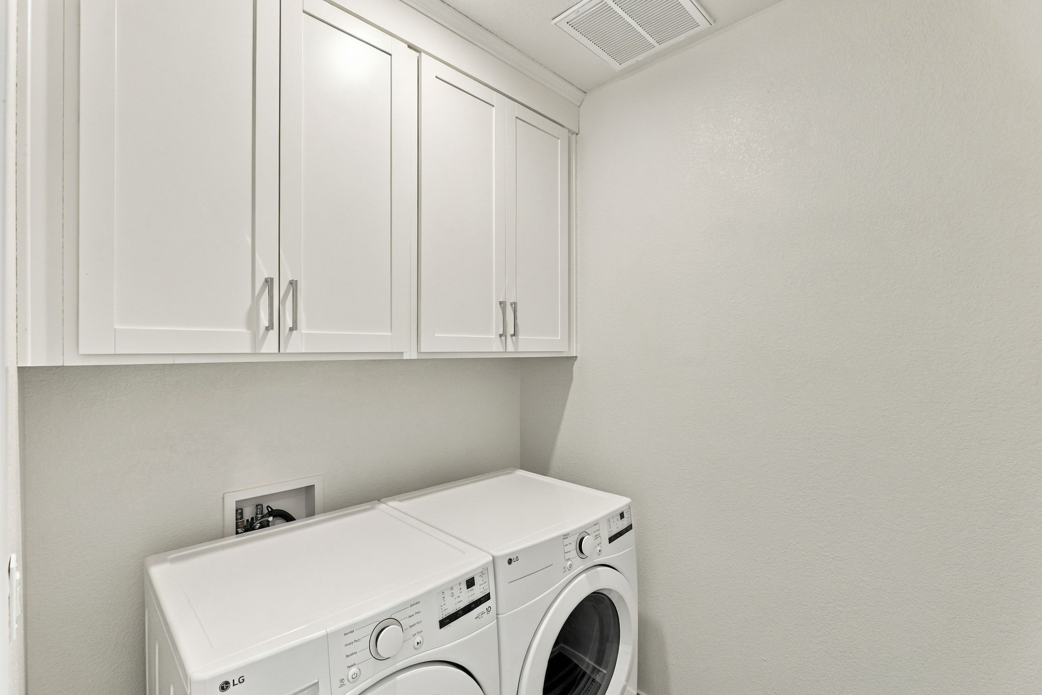 A white laundry room with white cabinets.