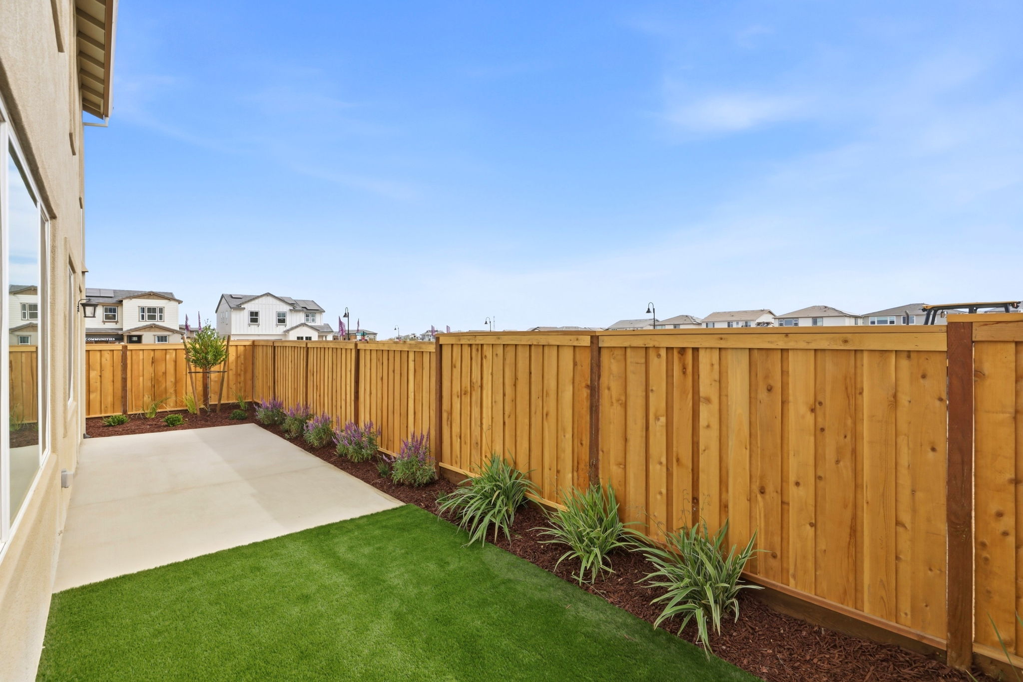 A fenced in yard with a house and plants.