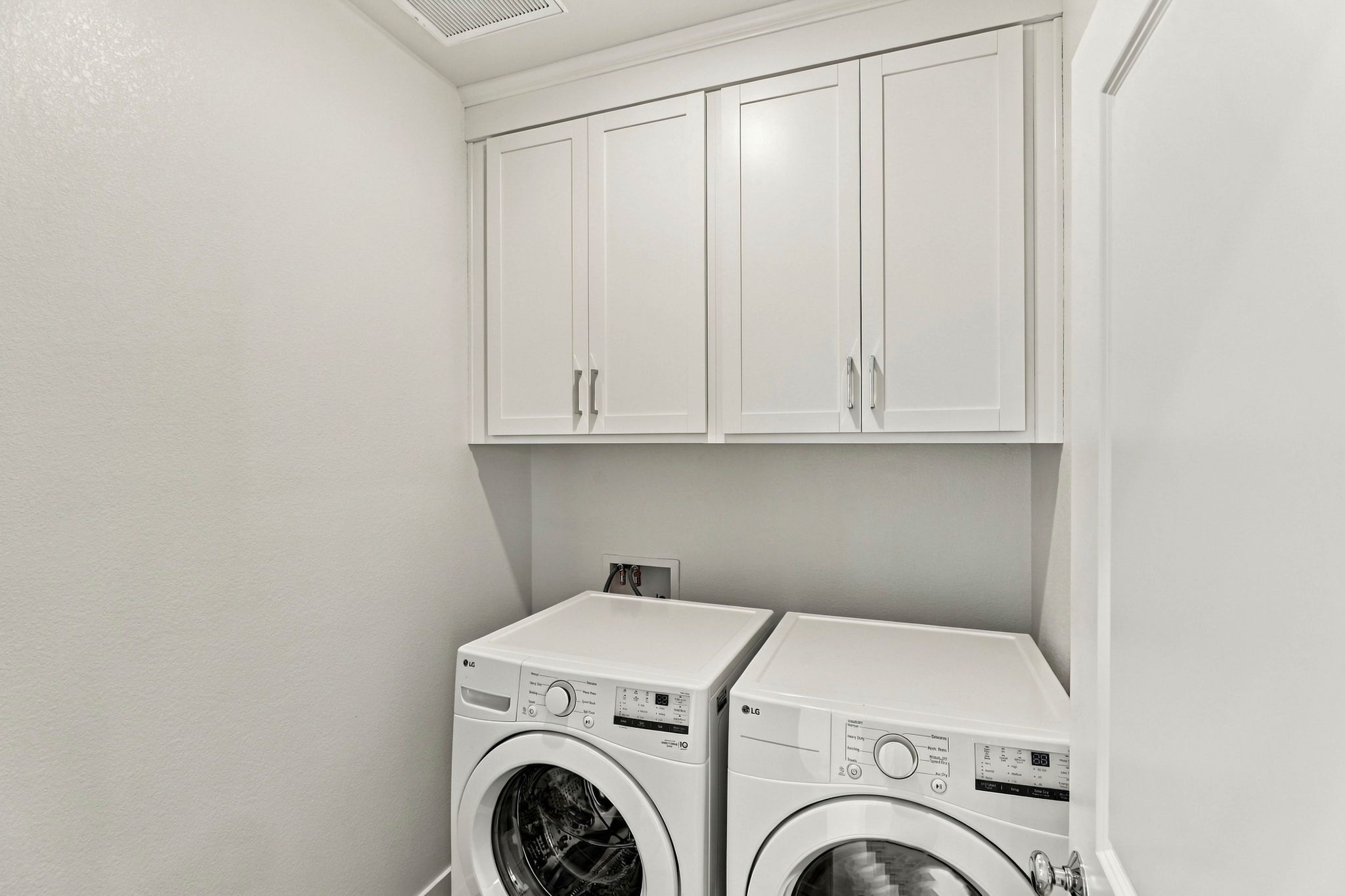 A white laundry room with white cabinets.