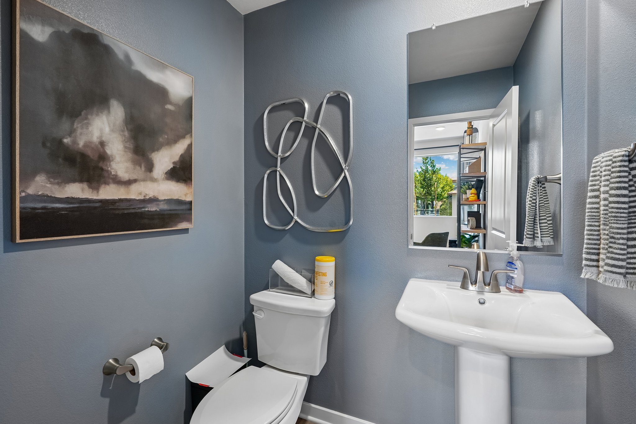 A bathroom with a sink toilet and a mirror.