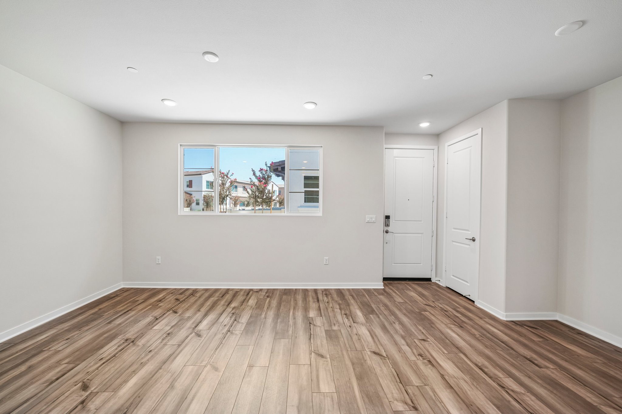 A room with a wood floor and a window with a view of a city.