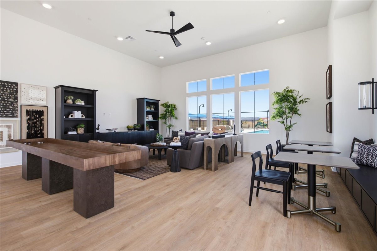 A large room with a wood floor and a wood floor with a table and chairs and a fan.
