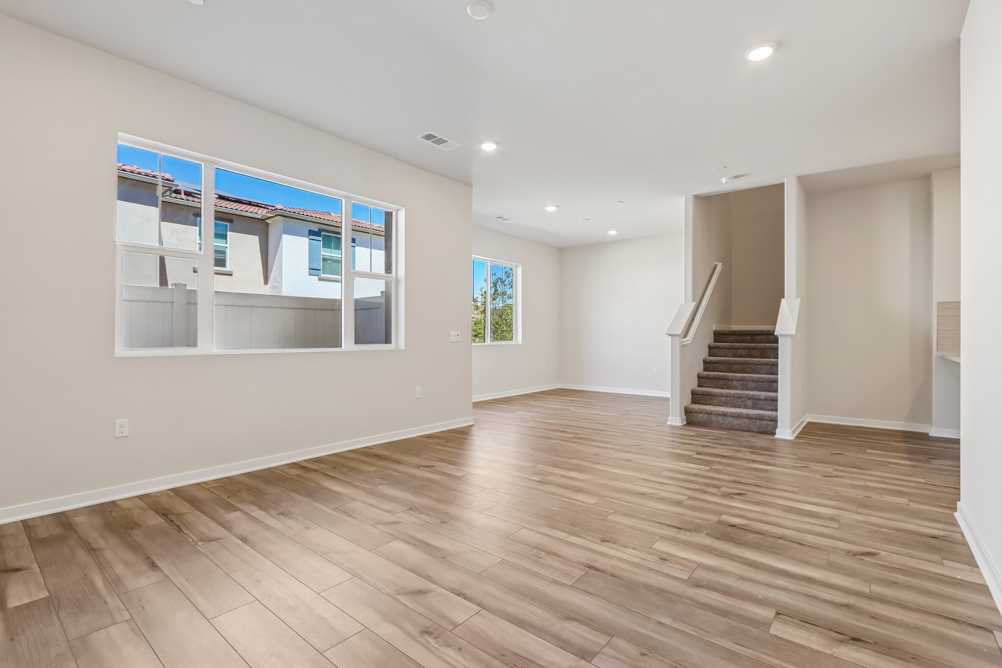 A large empty room with a wood floor and a staircase.