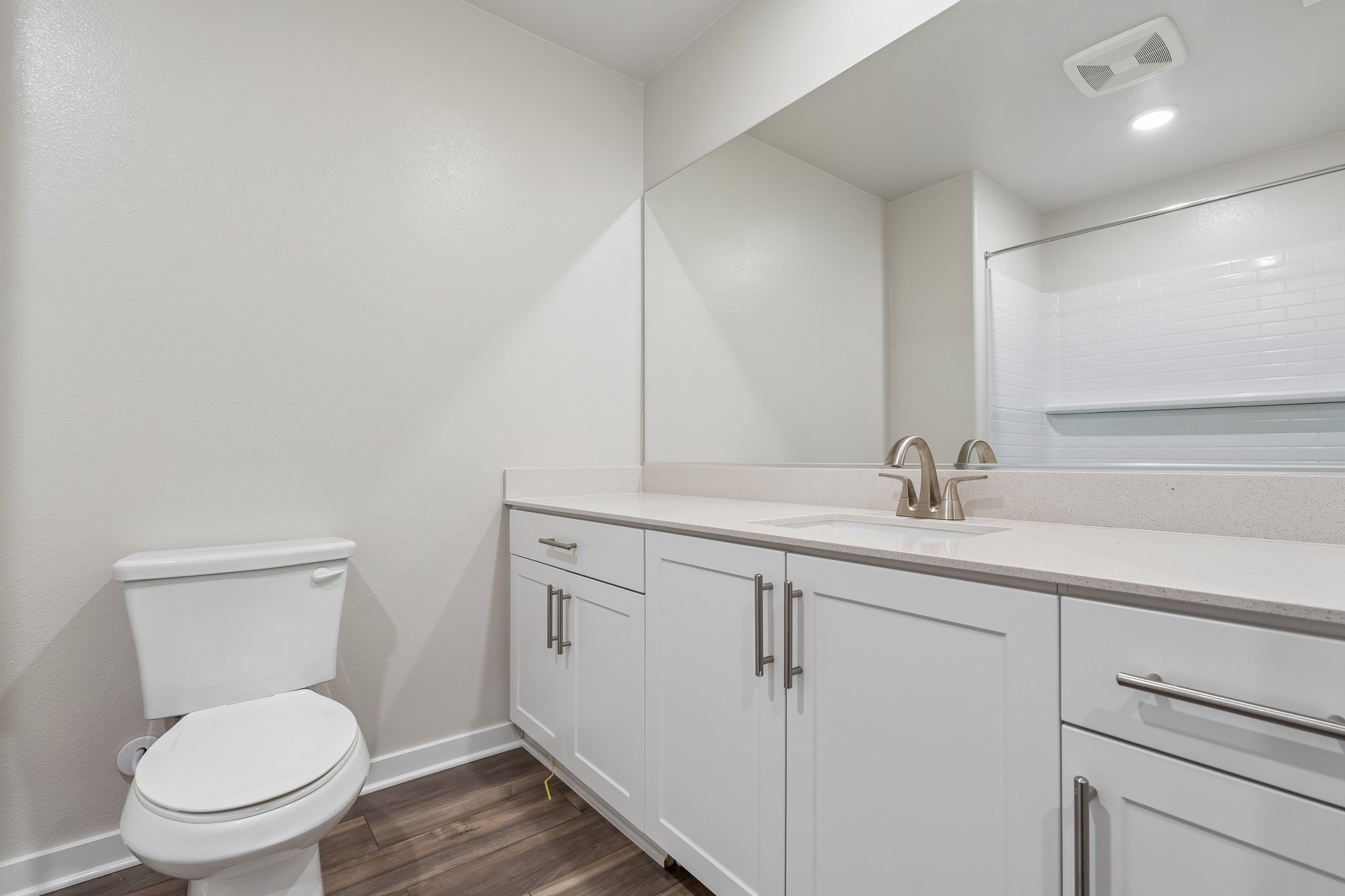 A bathroom with white cabinets.