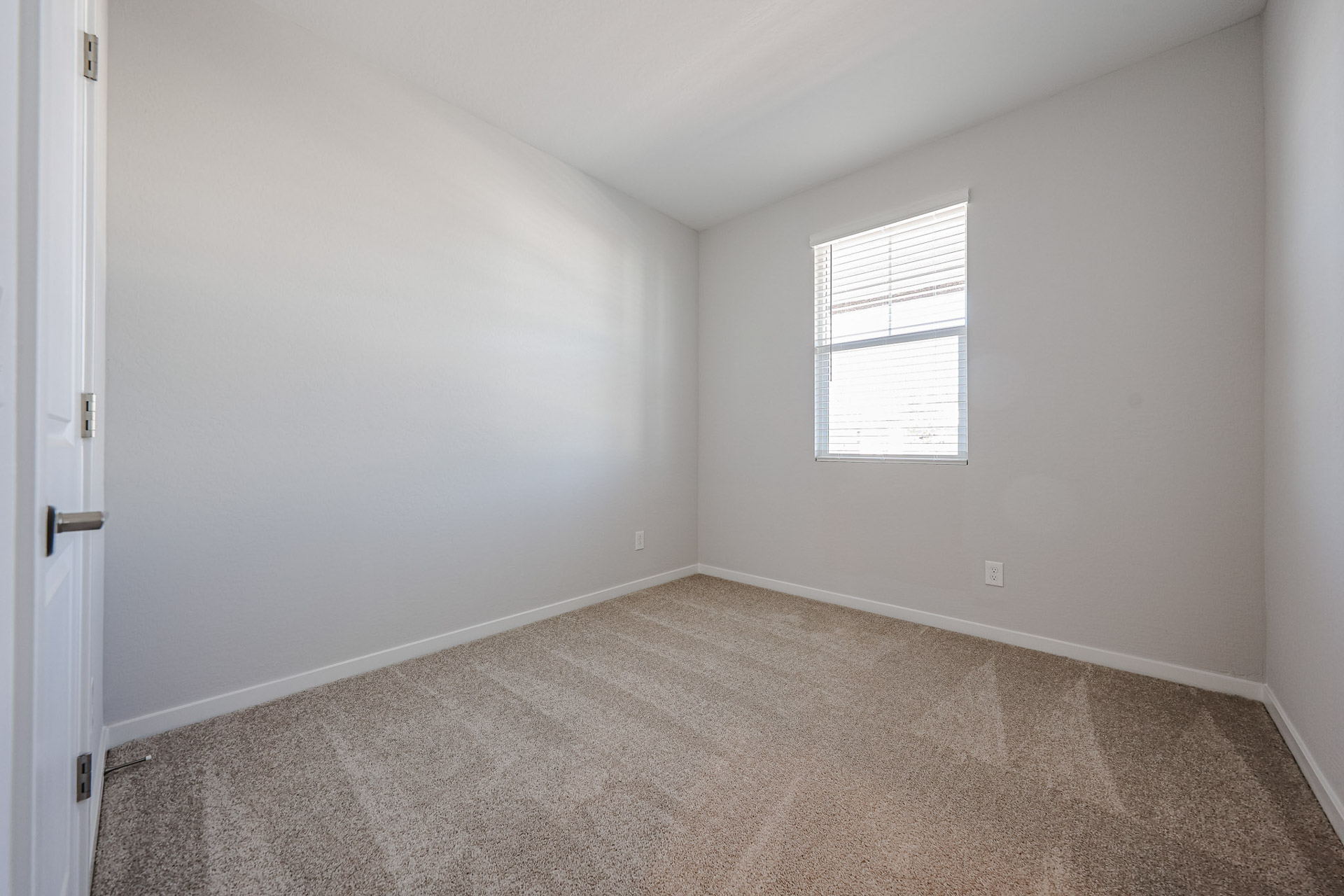 A room with a carpet and a door.