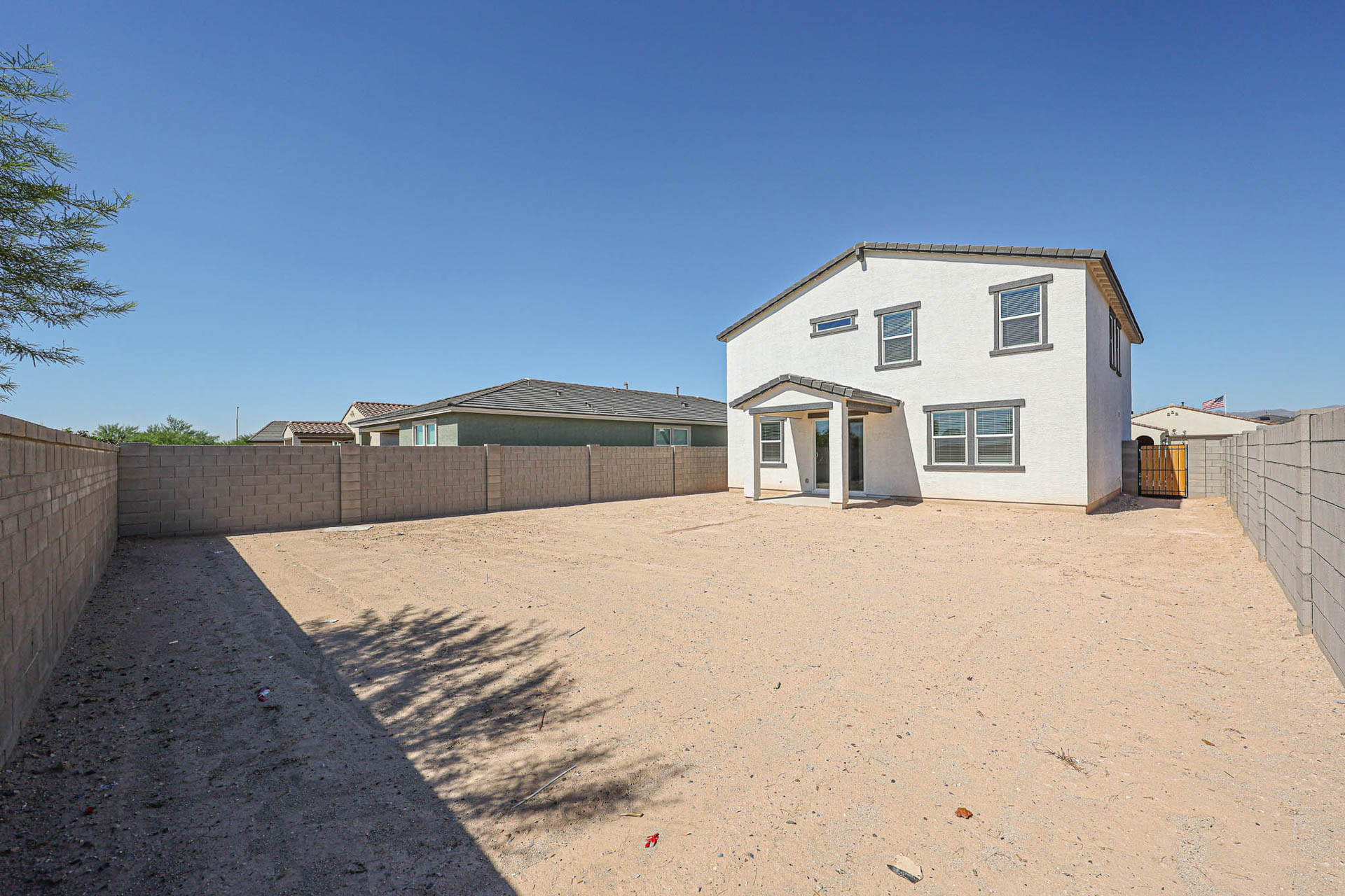 A dirt road with a fence and a house on the side.