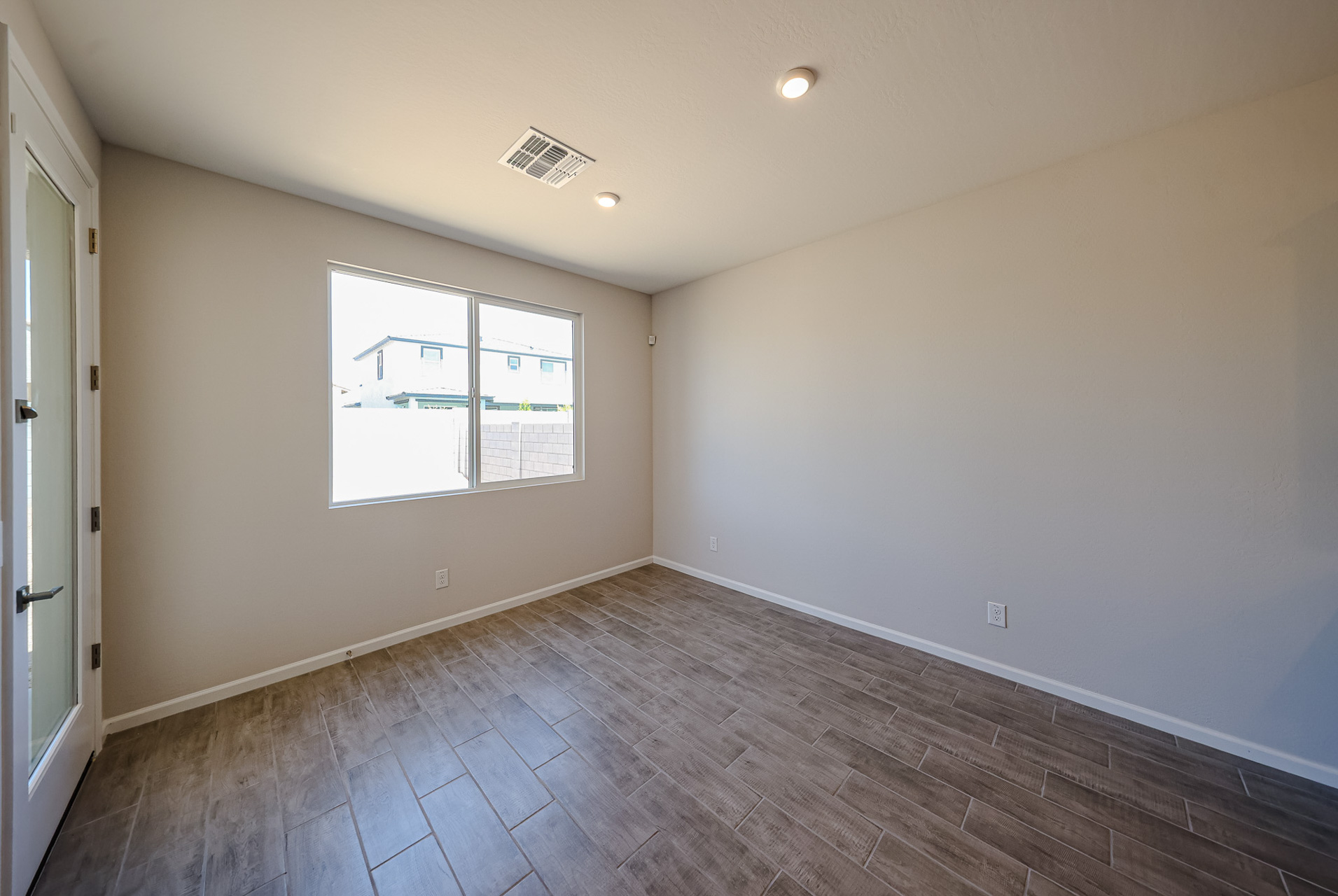 A room with a wood floor and a window with blinds.