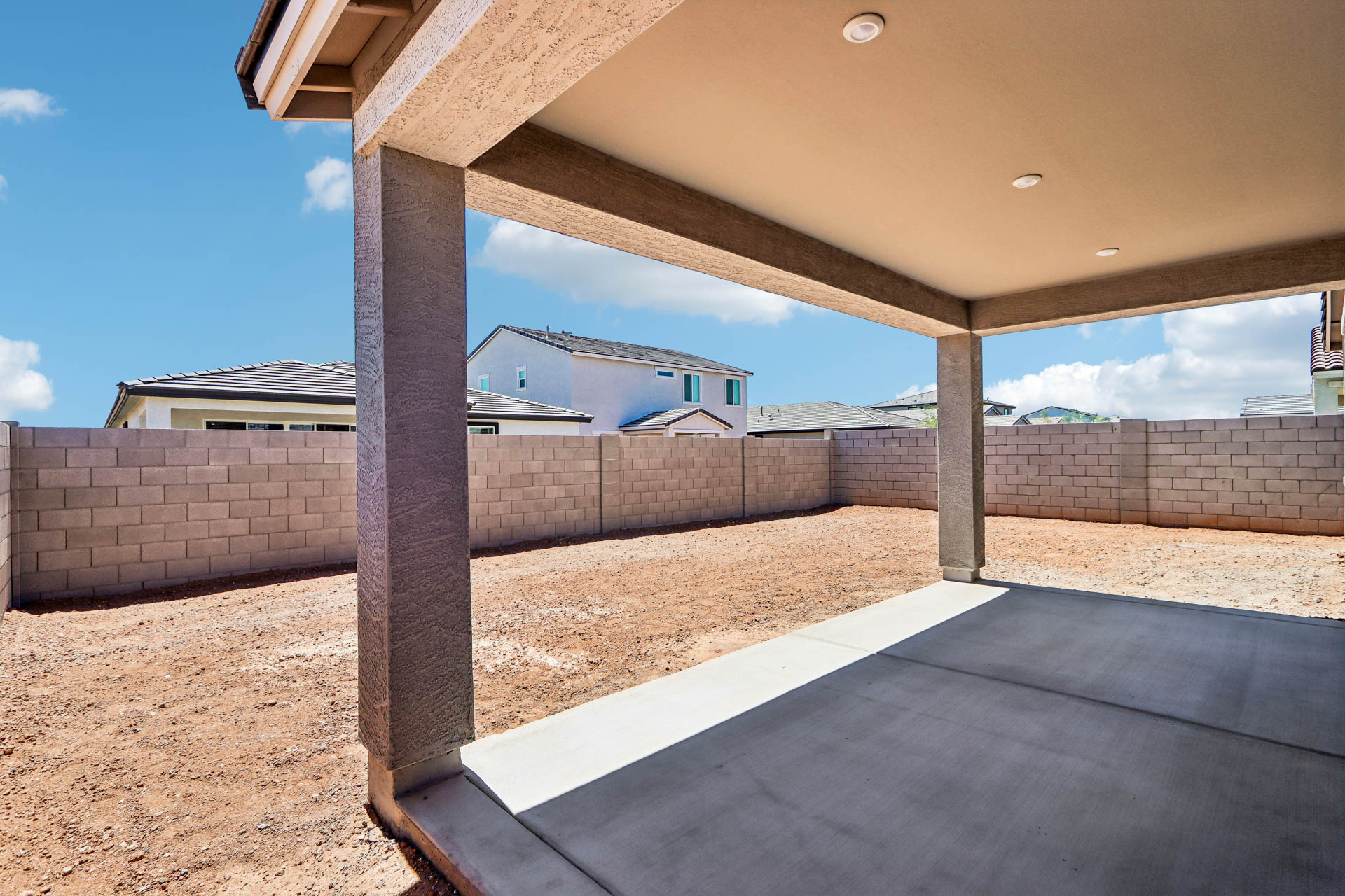 A concrete walkway with a stone wall and a building in the background.