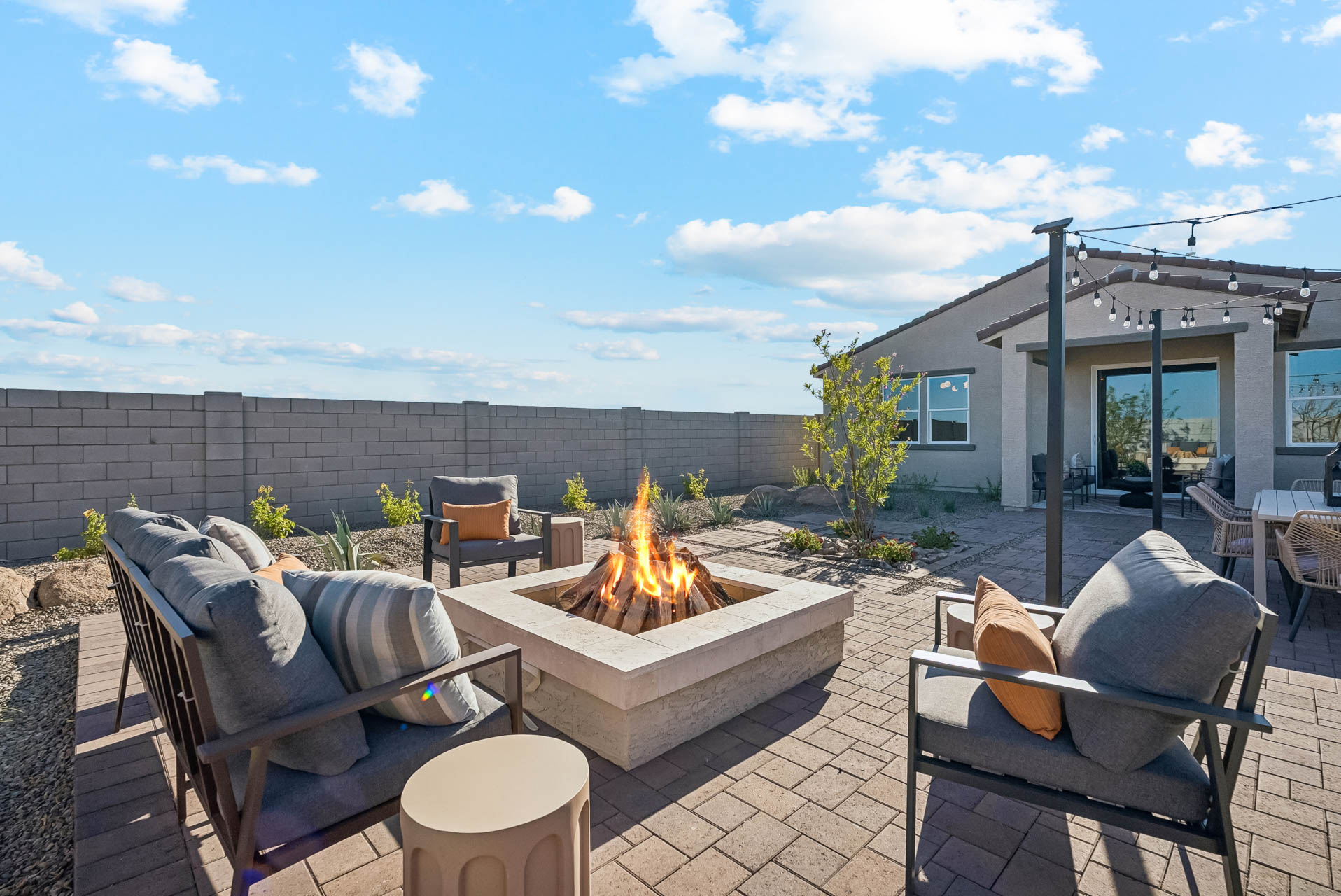A patio with chairs and a fire pit with a fire in it.
