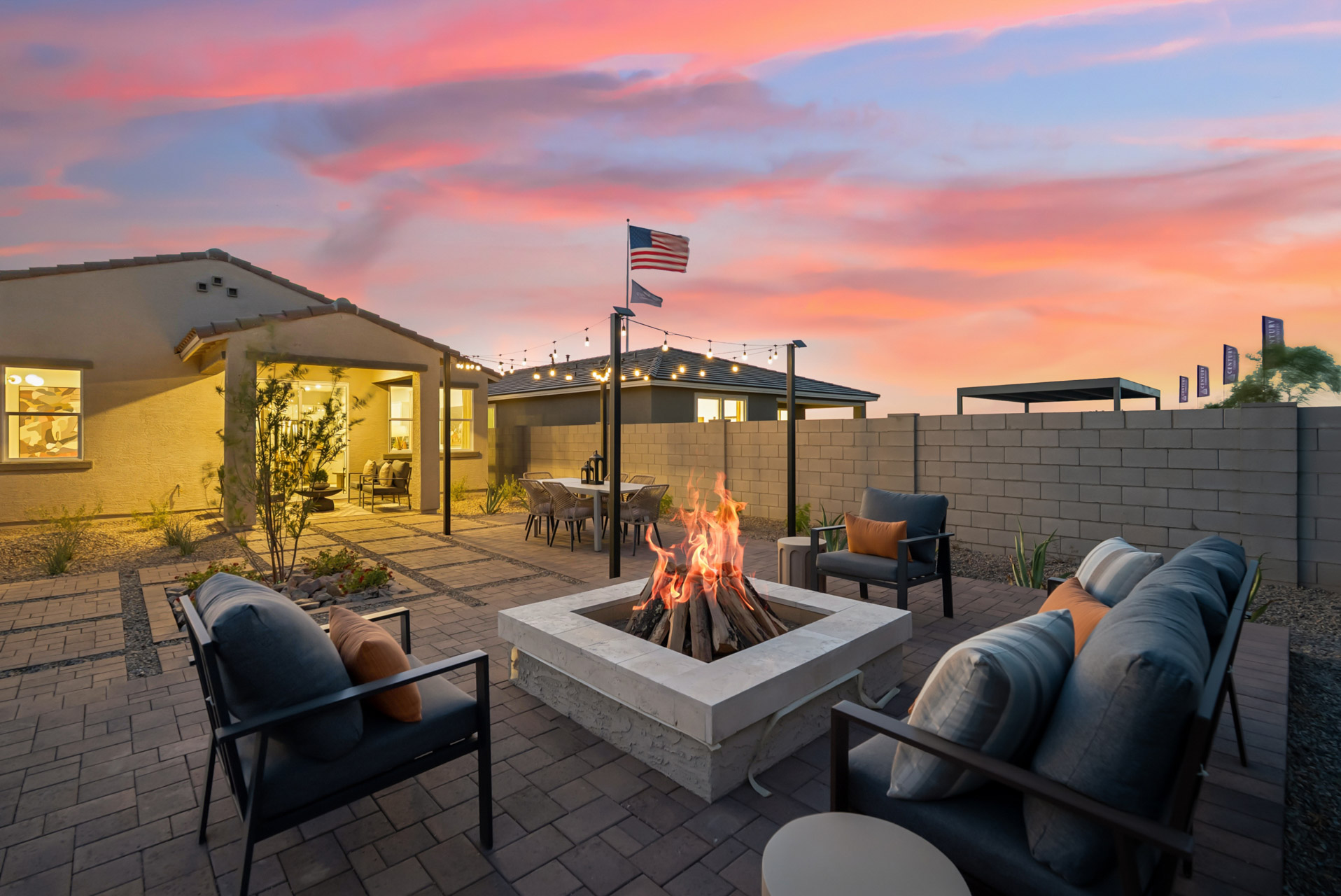 A patio with a fire pit and chairs and a fire pit.