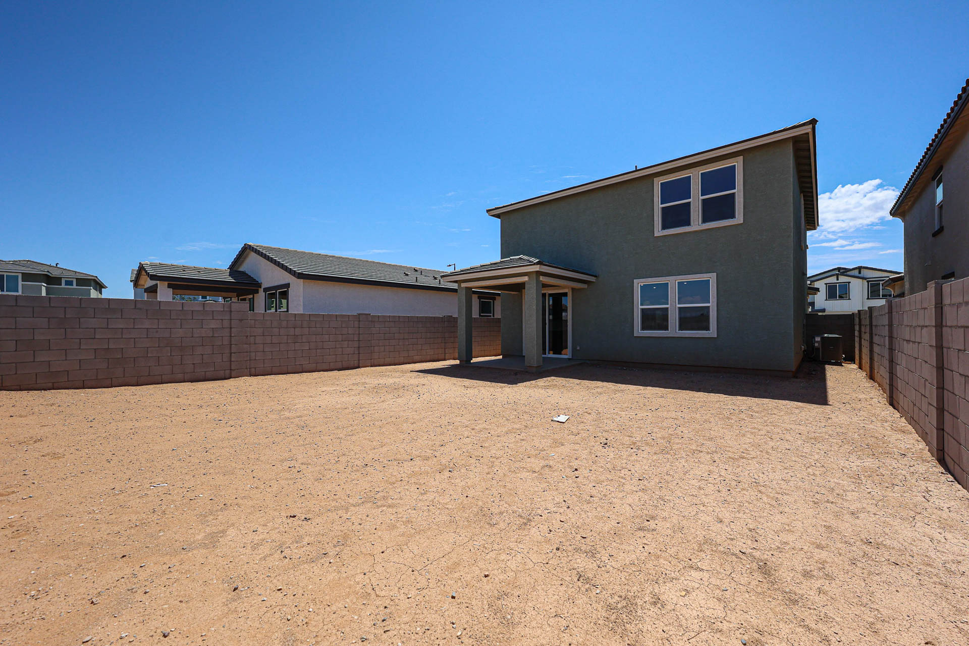 A dirt yard with a house in the background.