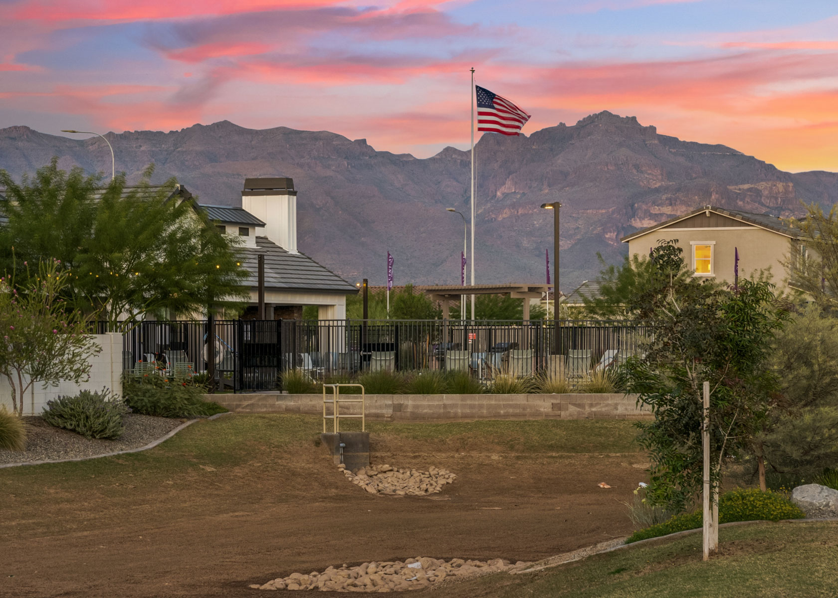 A flag on a pole in front of a building with a mountain in the background.