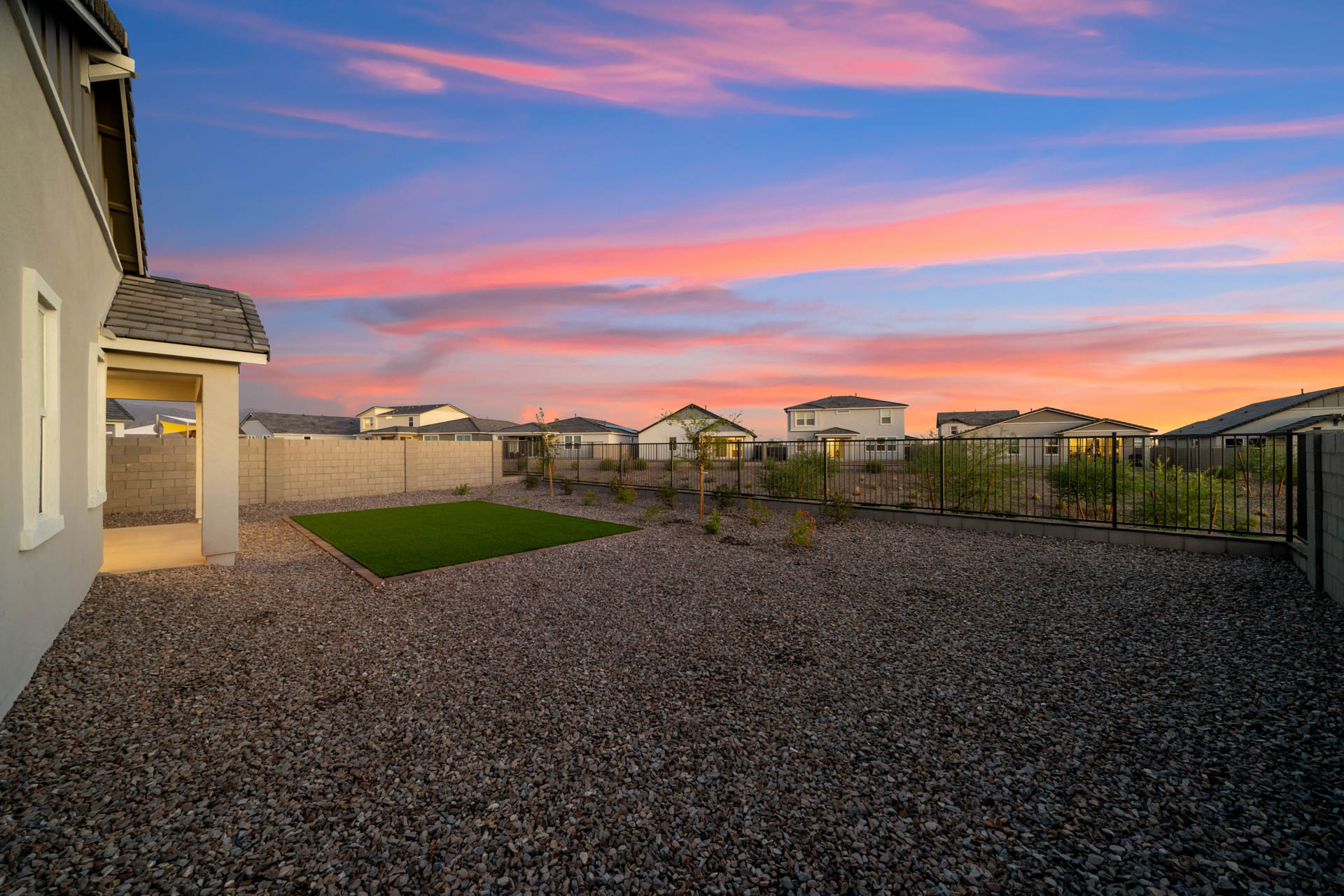 A backyard with a fence and a yard with houses in the background.