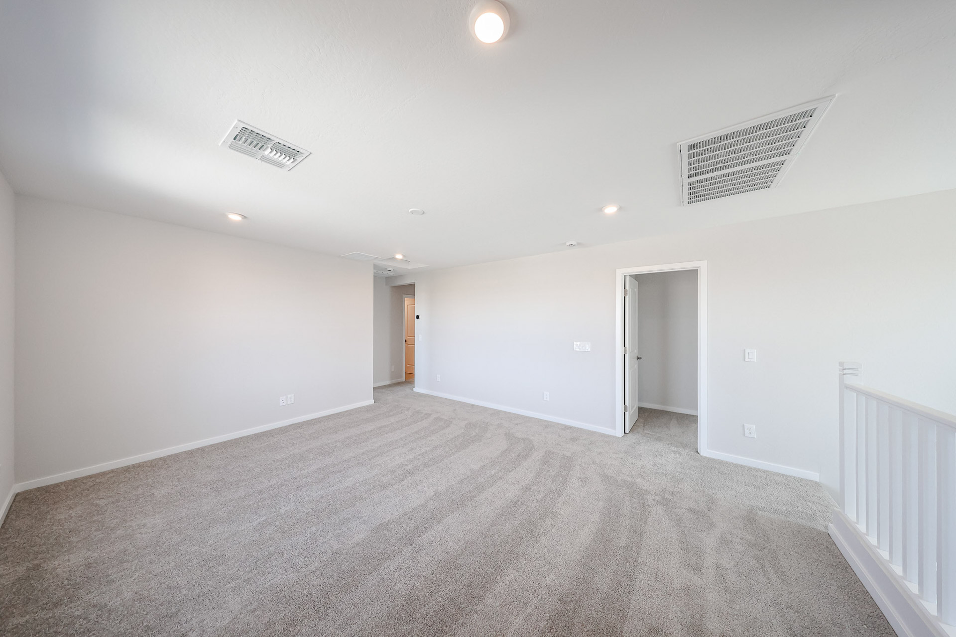A room with a carpet and a white railing.