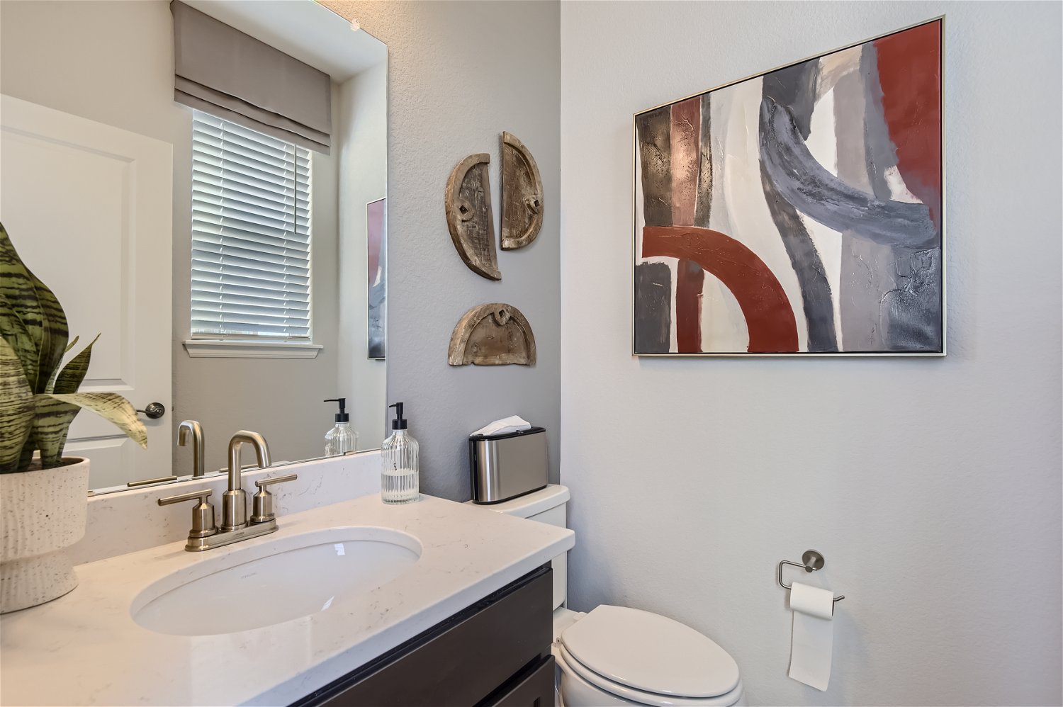 A bathroom with a sink toilet and a painting on the wall.