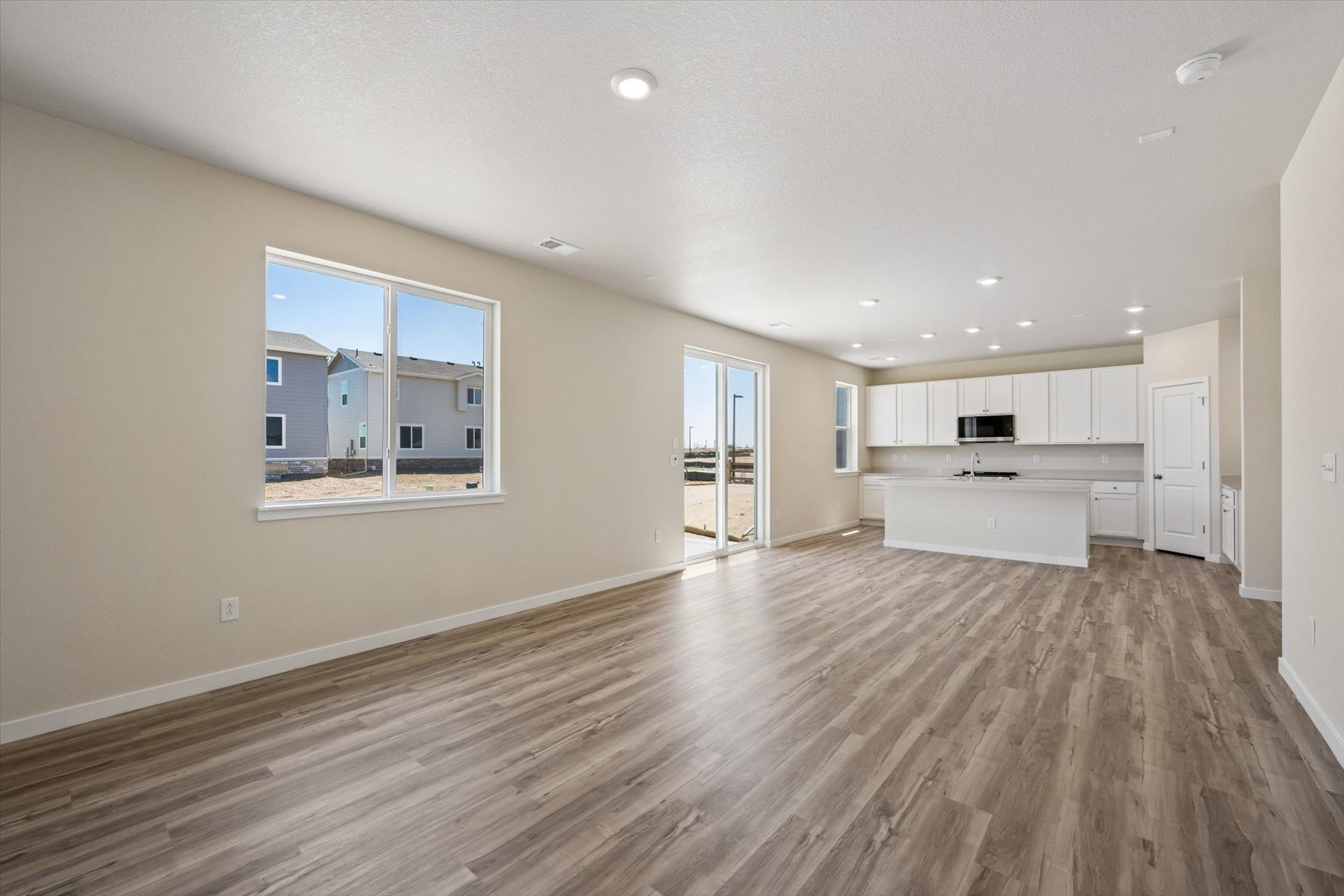 A large empty room with a wood floor and white cabinets.