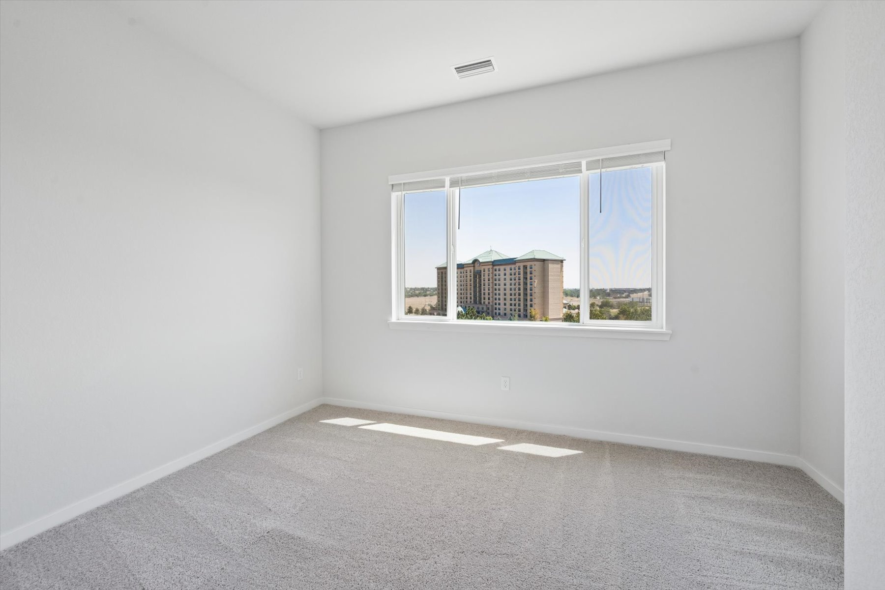 A room with a window and a view of a city.