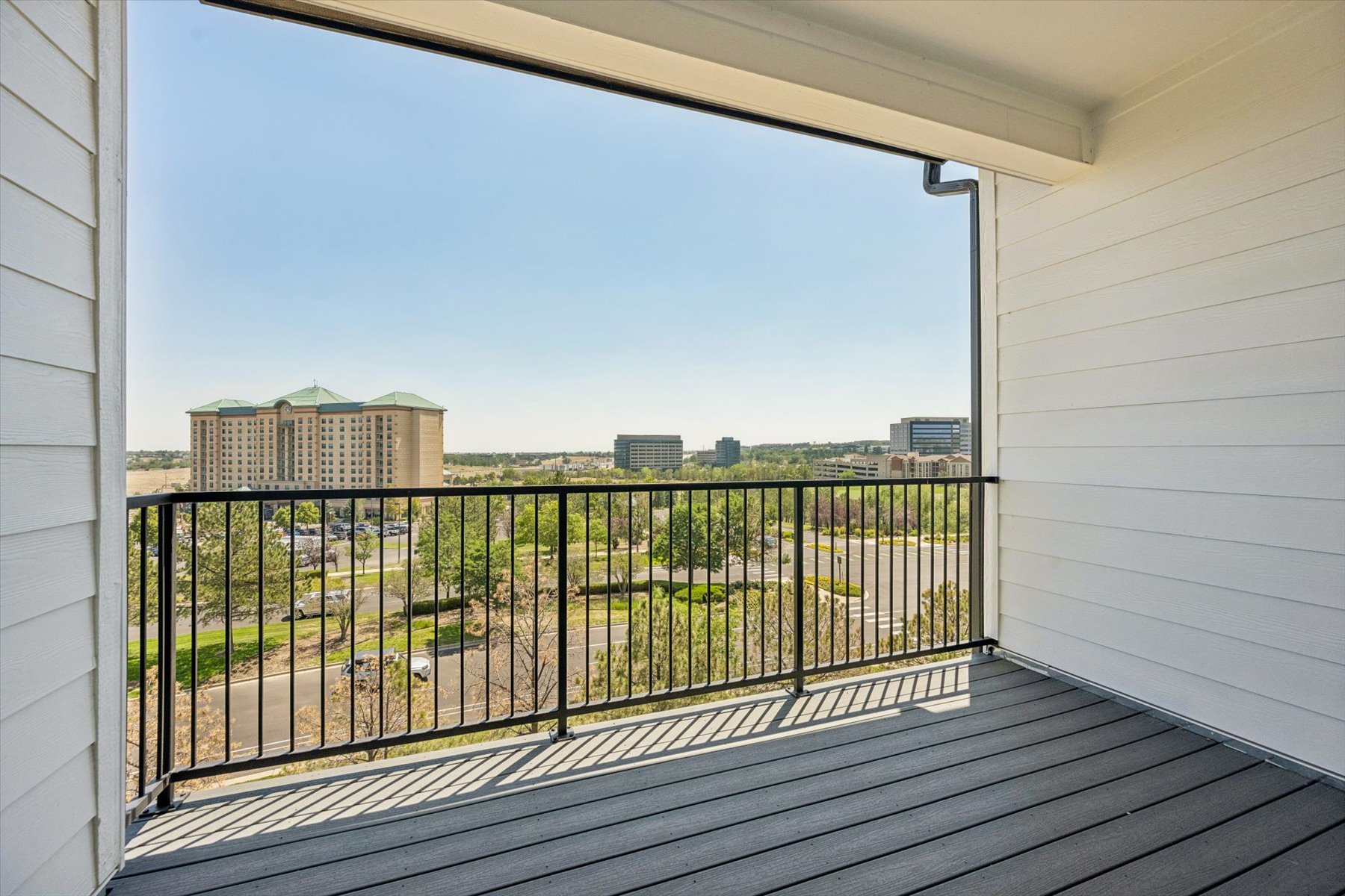A deck with a railing and buildings in the background.