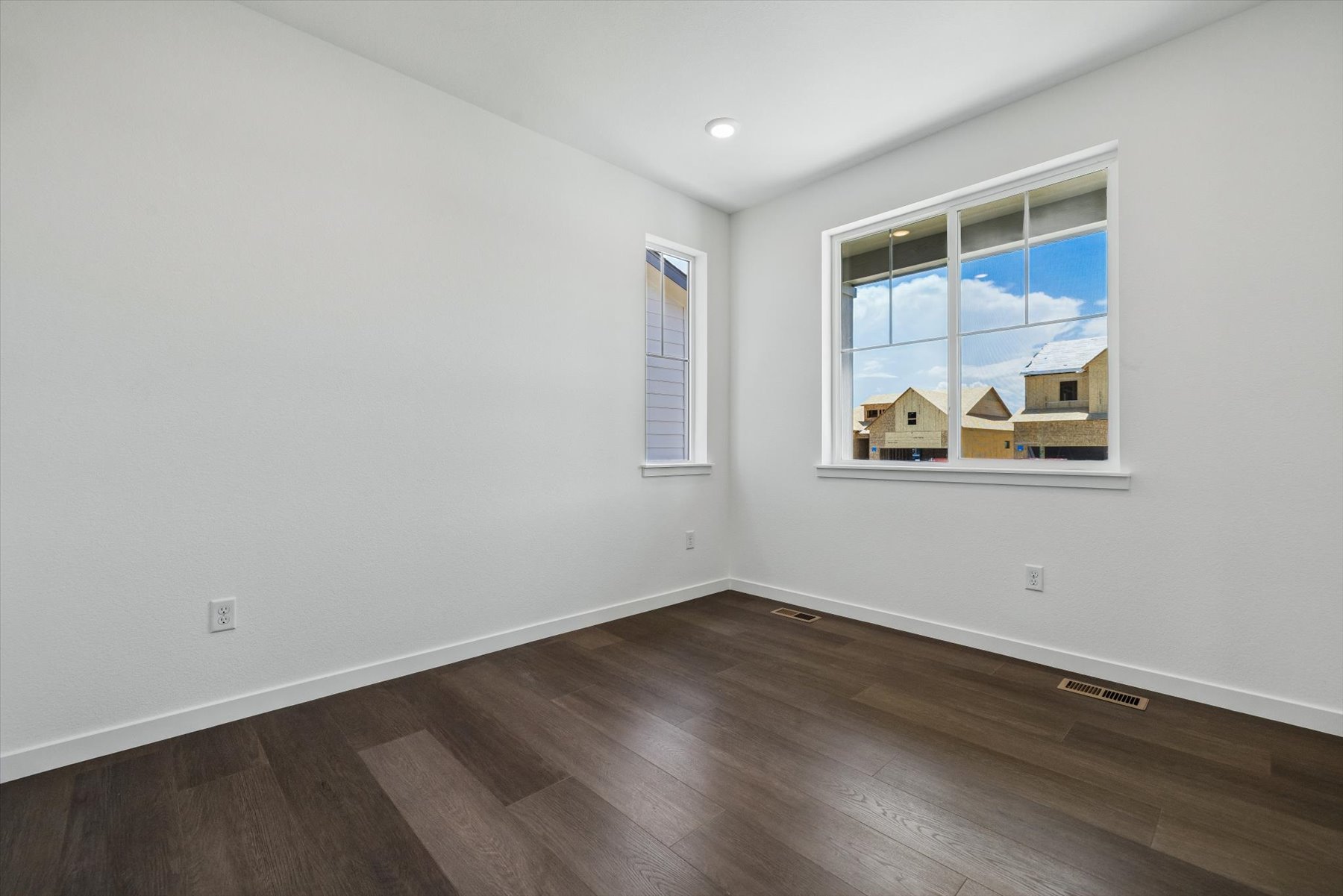 A room with a wood floor and a window with a view of a city.