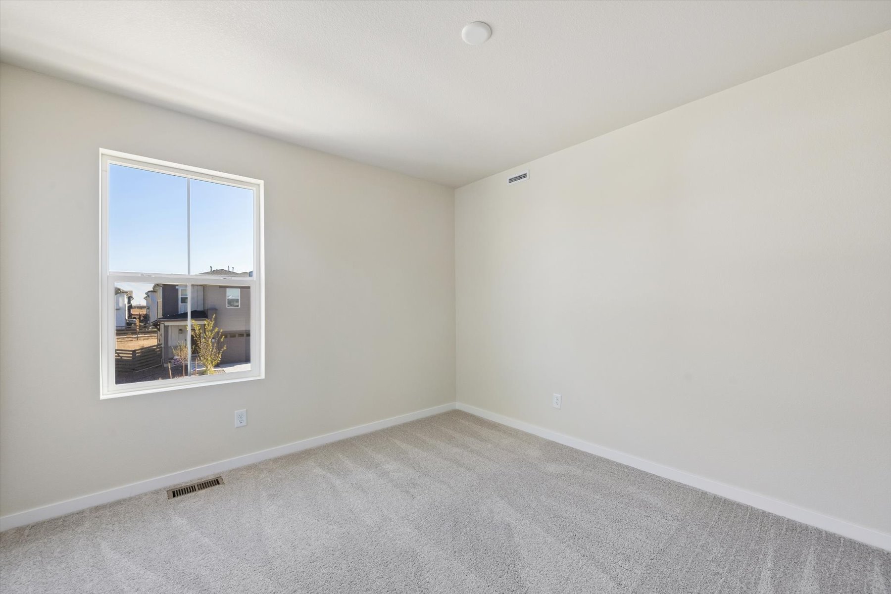 A room with a window and a white wall.
