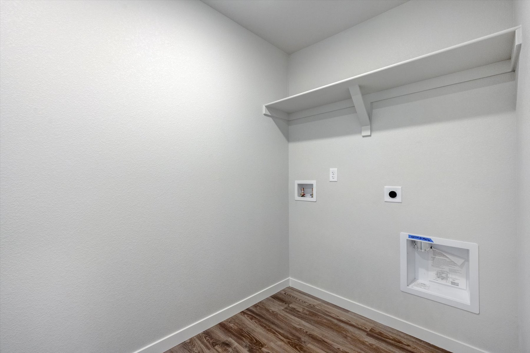 A white wall with a wood floor.
