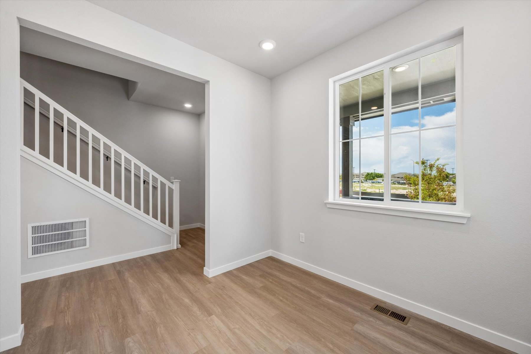 A room with a wood floor and a window with a railing.