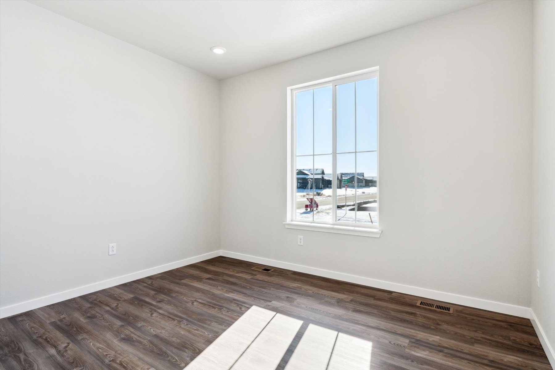 A room with a window and a wood floor.