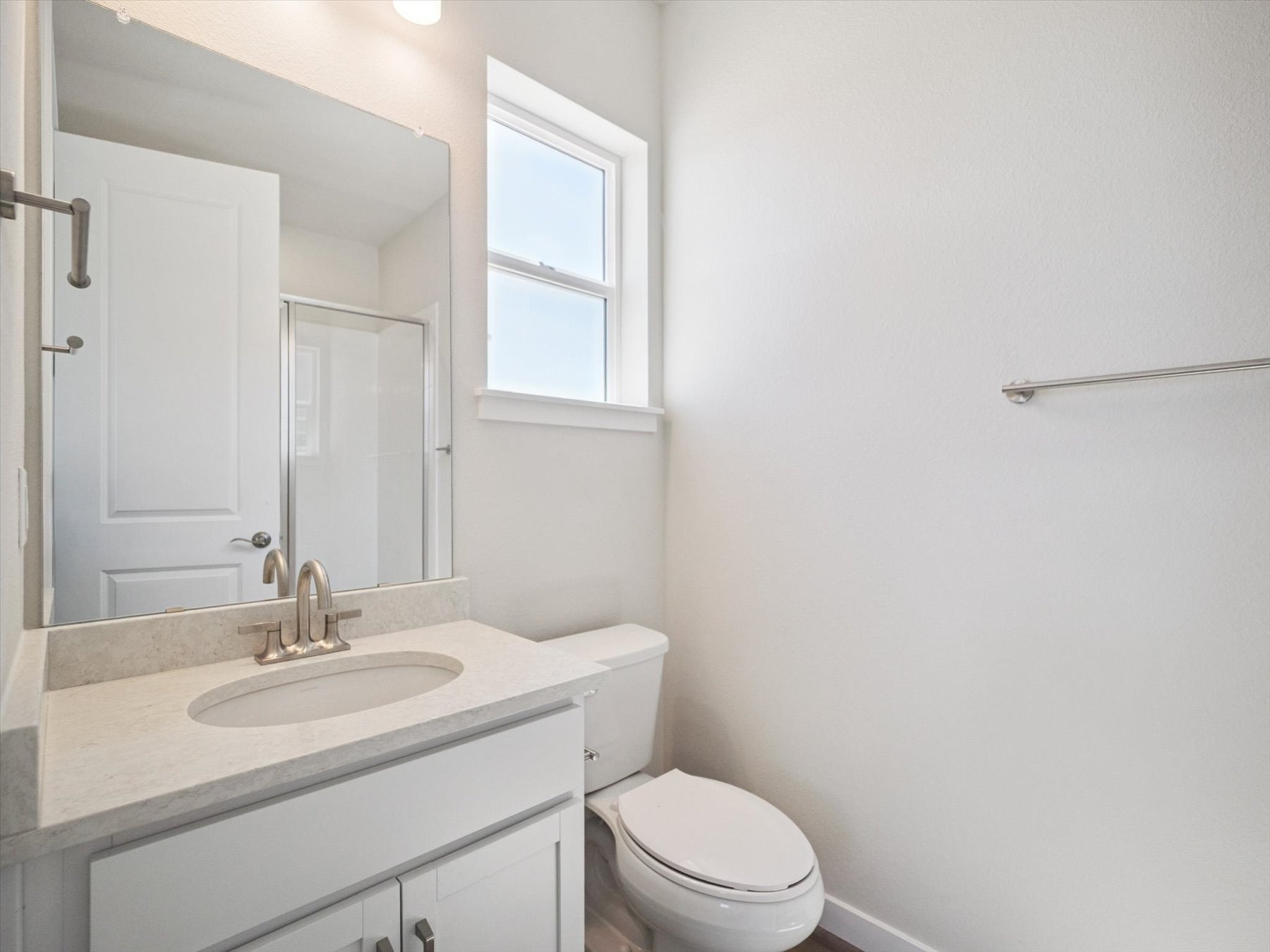 A bathroom with a sink toilet and mirror.
