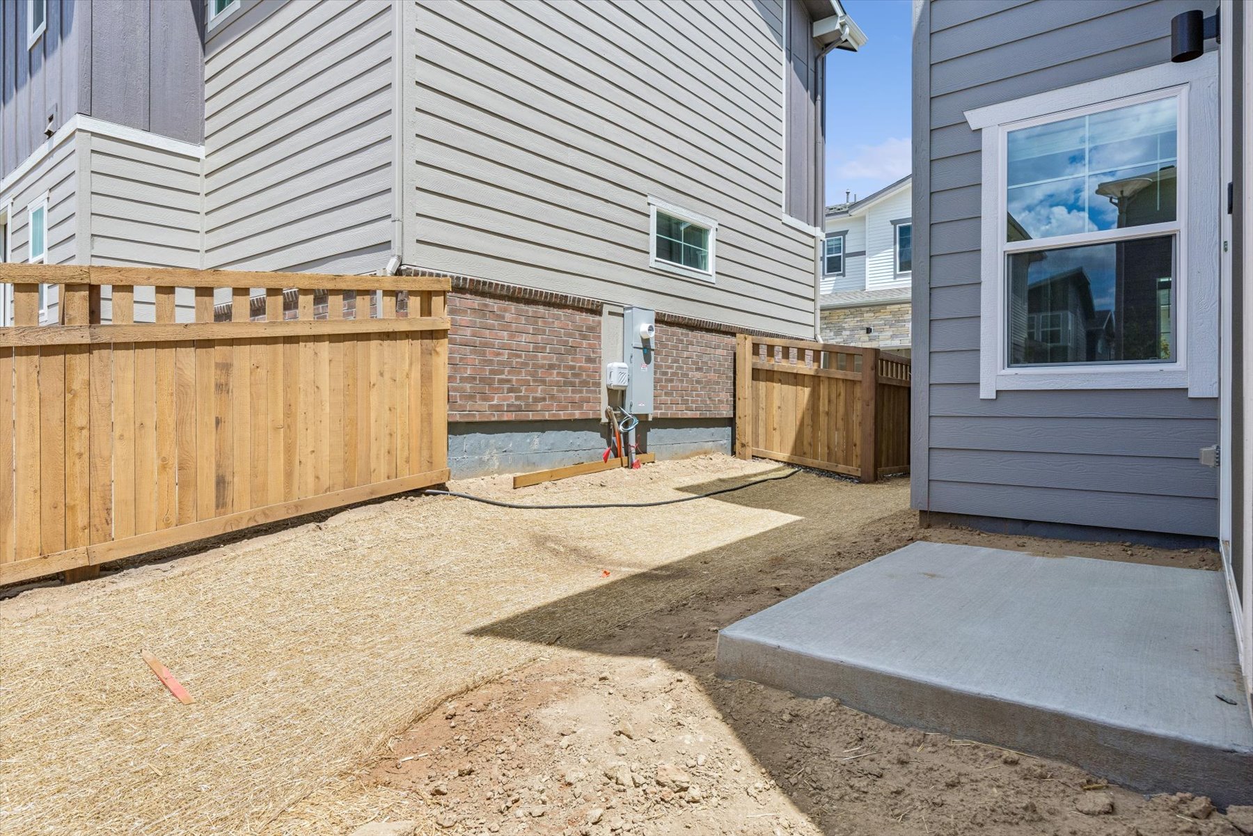 A backyard with a fence and a brick building.