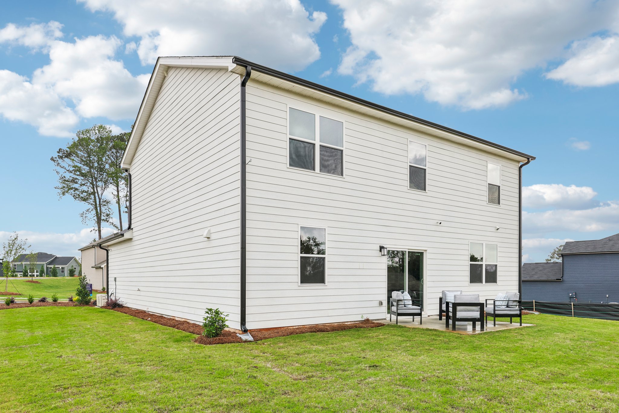 A white house with a lawn with Rockingham Meeting House in the background.