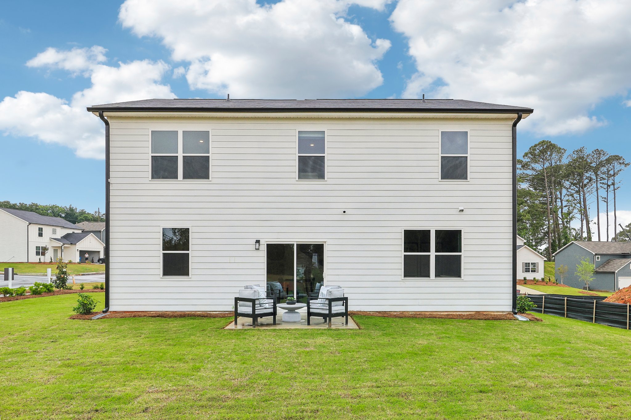 A house with a yard and a table and chairs in front.