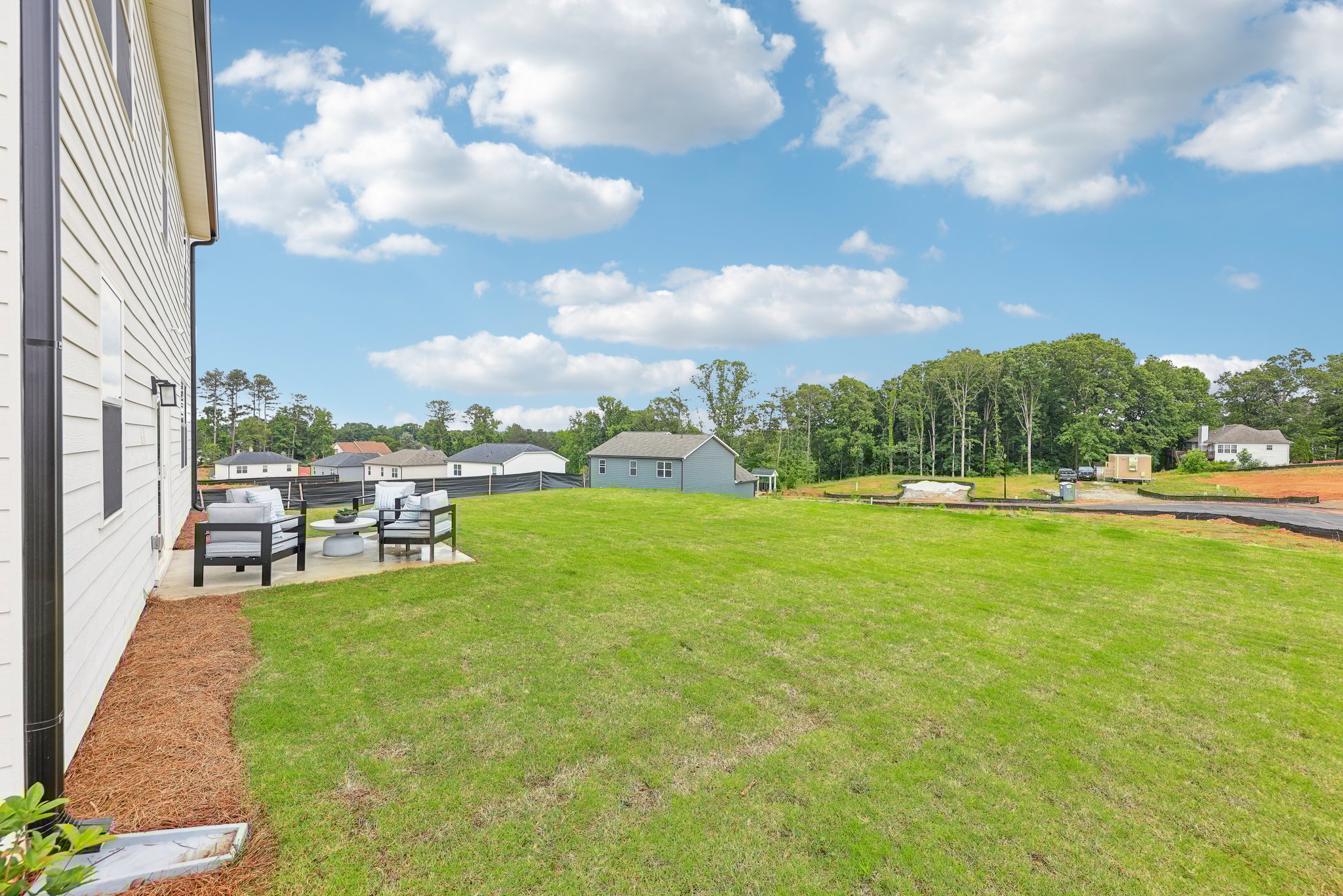 A grassy field with a building and trees in the background.