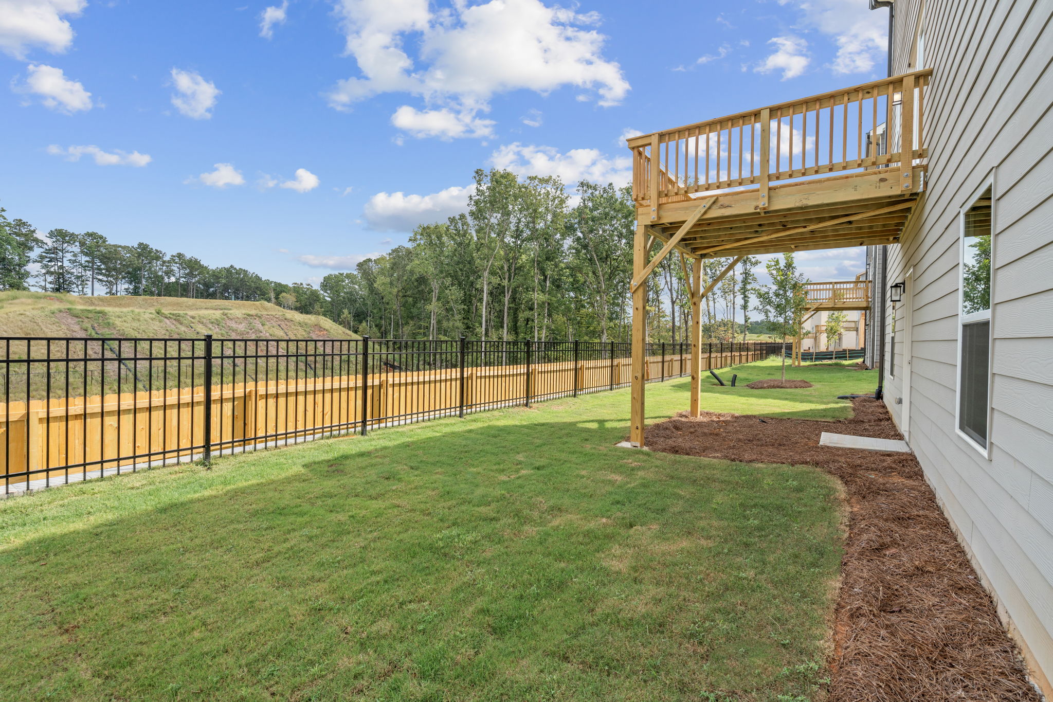 A fenced in yard with a wood structure and trees in the background.