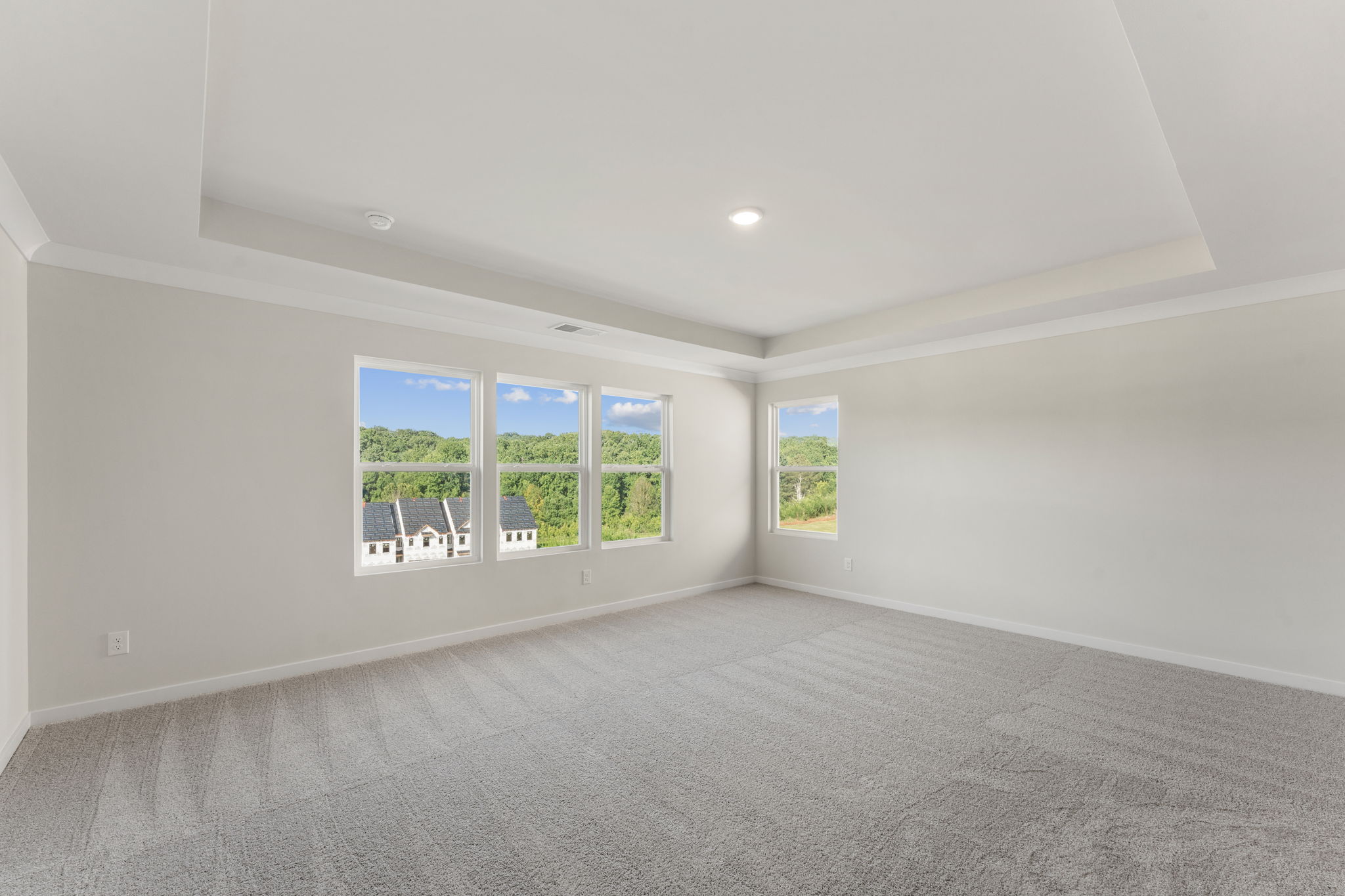 A room with a large window and a large white wall with a chair and a table and chairs.