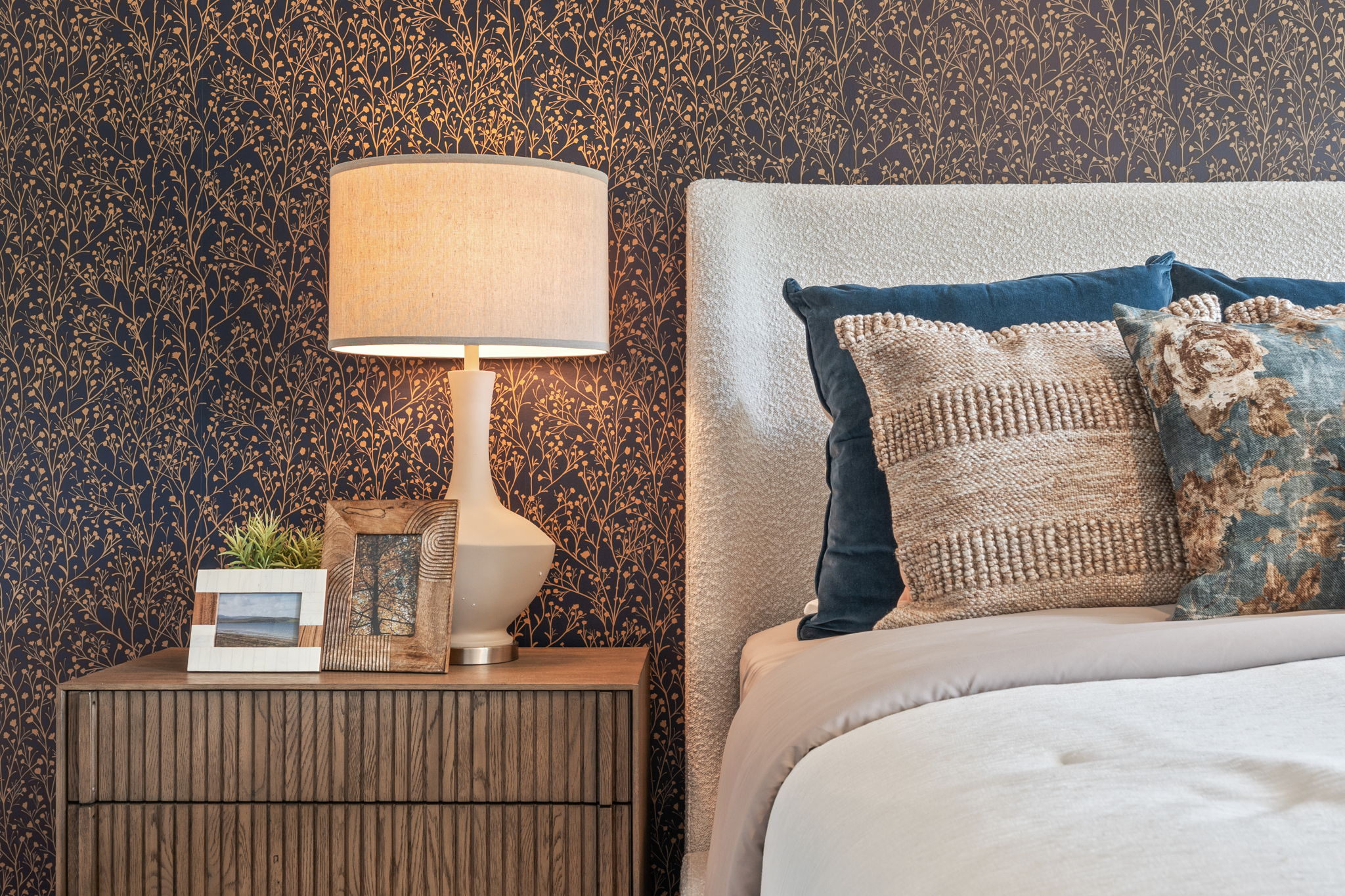 A bed with a lamp and pillows.