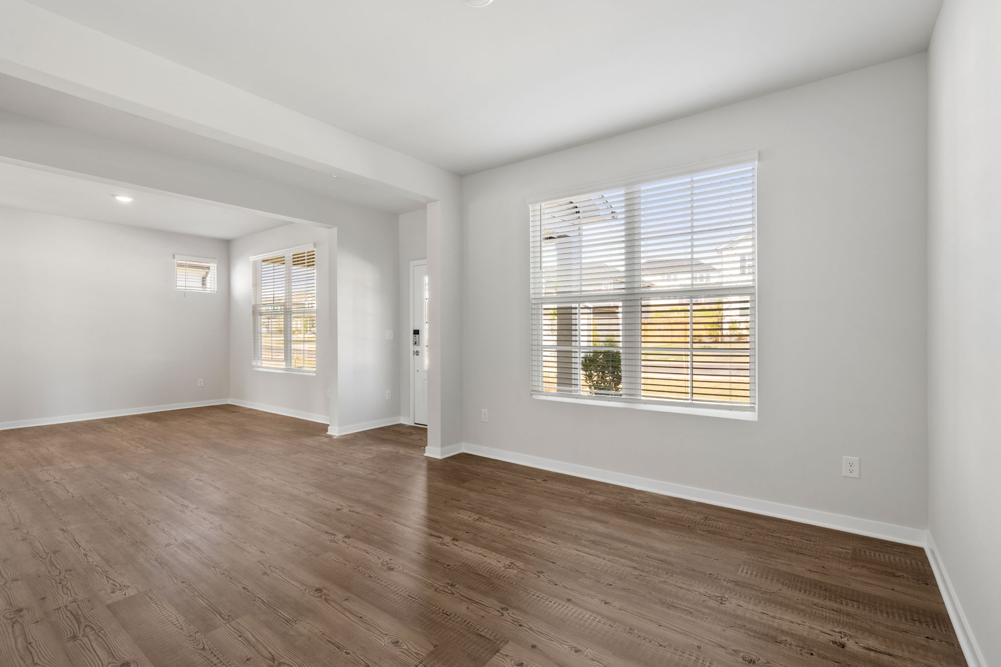 A room with a wood floor and a window with blinds.