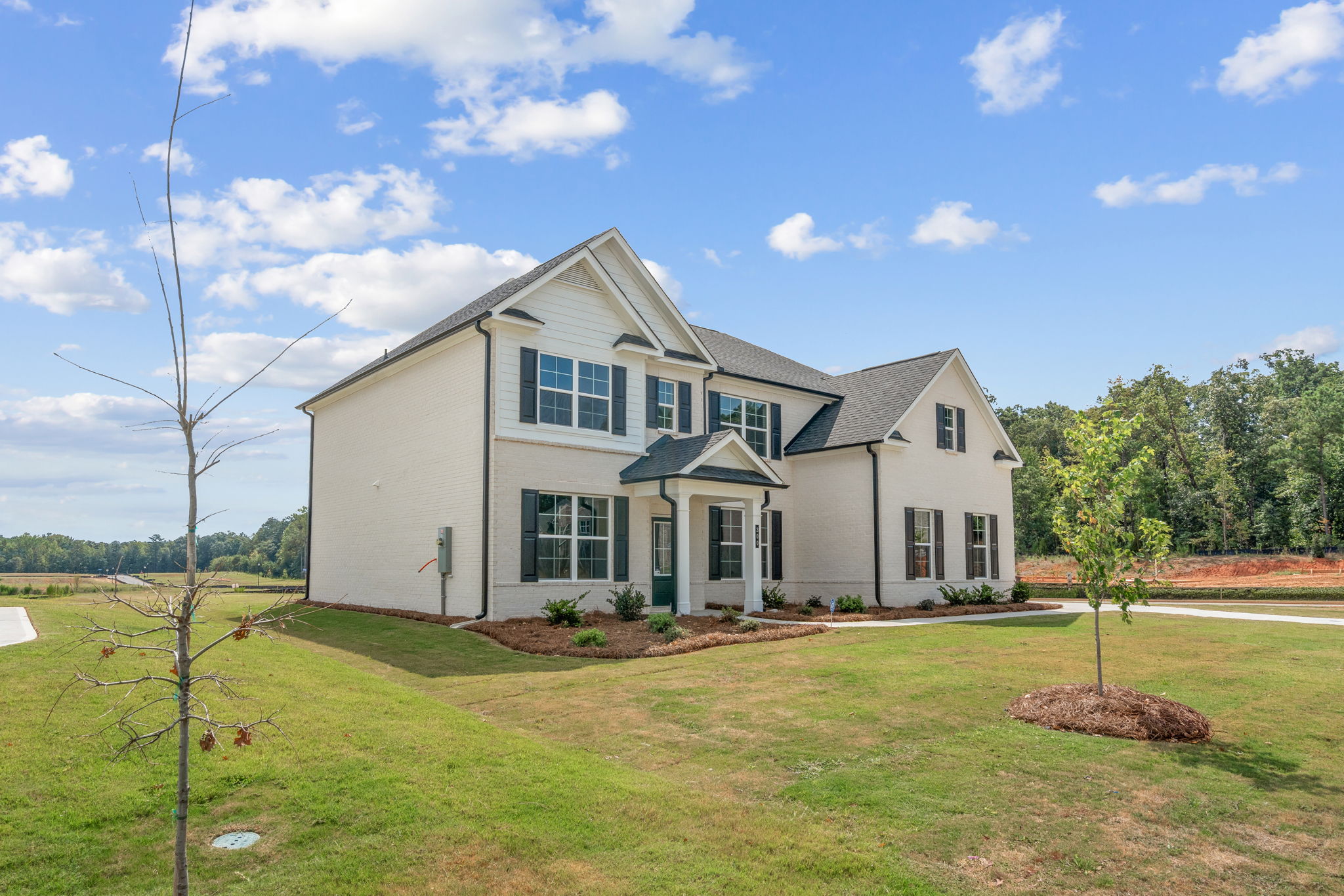A large house with a lawn and trees in front of it.