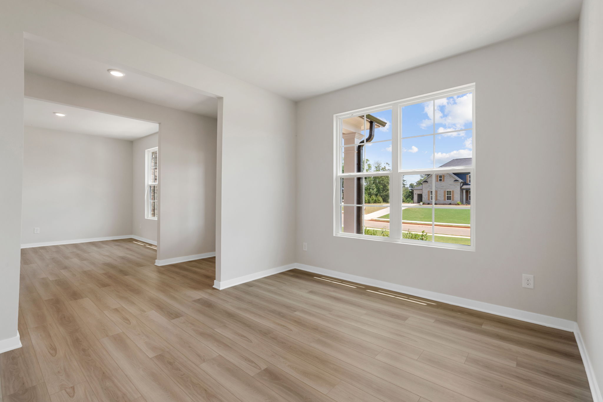 A room with a wood floor and a window with a view of the ocean.